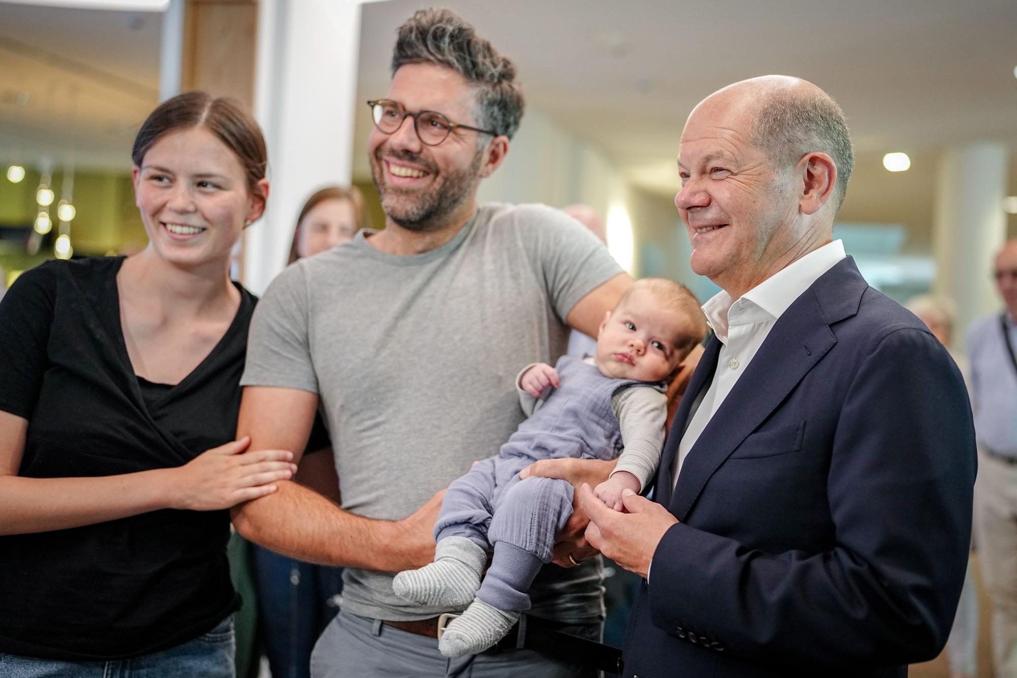 09.06.2024, Brandenburg, Potsdam: Bundeskanzler Olaf Scholz (r, SPD) steht nach seiner Stimmabgabe für die Europawahl in seinem Wahllokal mit Elisabeth und Valentin Jahn (l-r) mit ihrem Baby Benedikt für ein Foto zusammen. Foto: Kay Nietfeld/dpa-Pool/dpa +++ dpa-Bildfunk +++