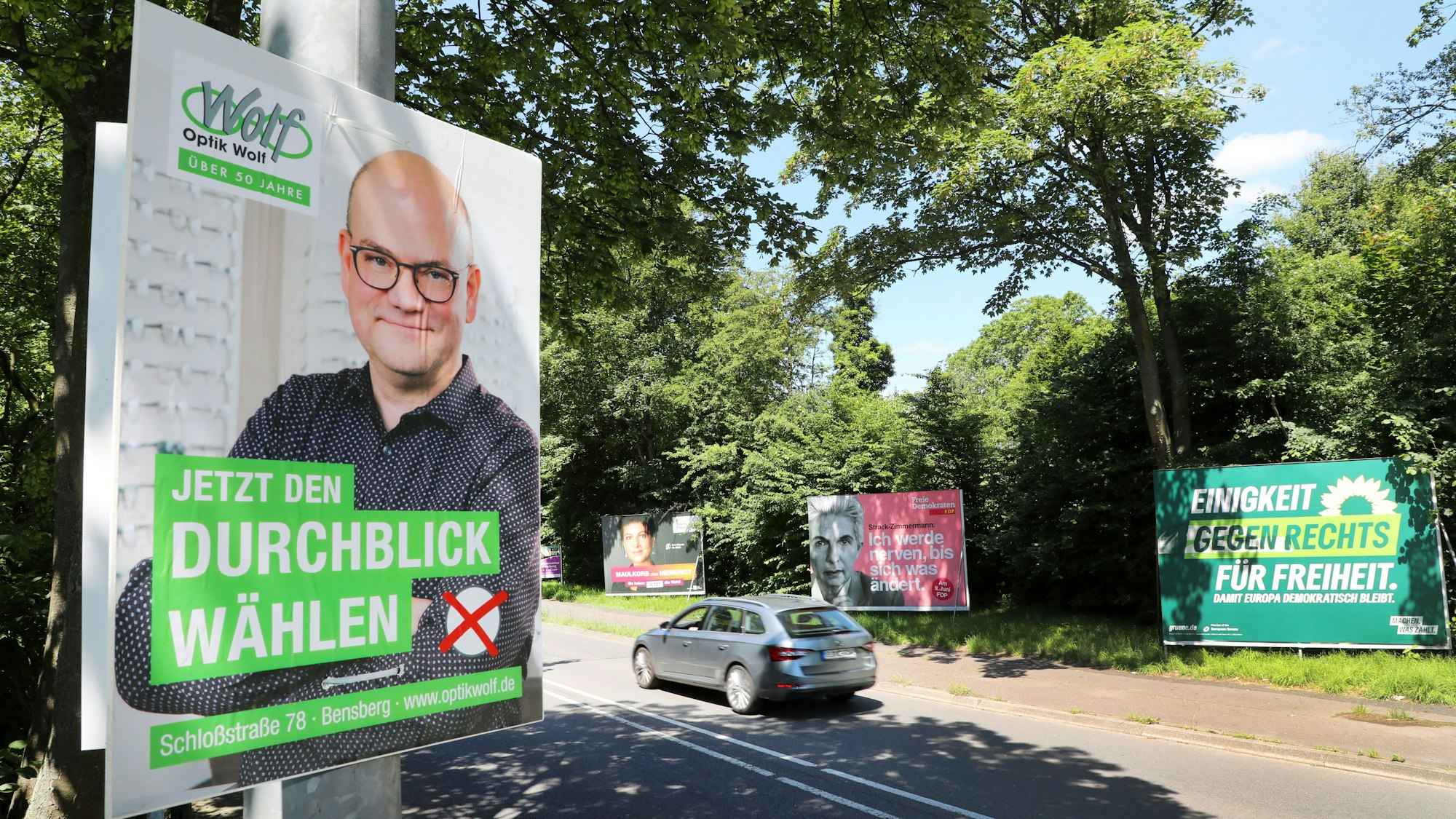 Neben Plakaten von Parteien zur Europawahl hängt ein der Wahlwerbung nachempfundenes Plakat eines Optikers, der für „Jetzt Durchblick wählen“ wirbt.