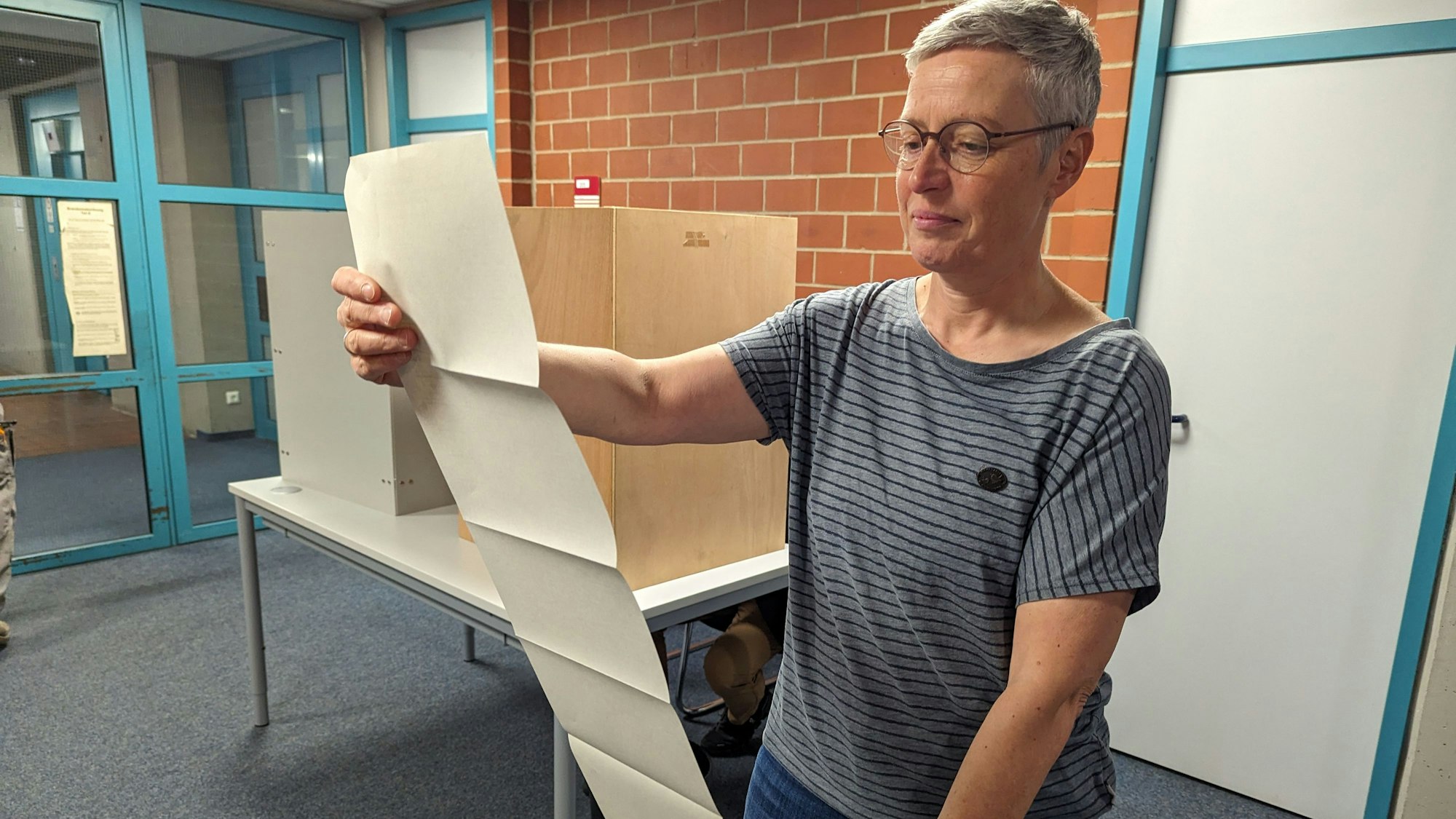 Auf dem Foto ist eine Frau zu sehen, die den Stimmzettel betrachtet.