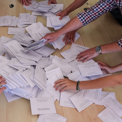 Sachsen-Anhalt, Halle: Zahlreiche Wahlhelfer nehmen sich bei der Stimmenauszählung die Umschläge mit den Briefwahlstimmen zur Europawahl.