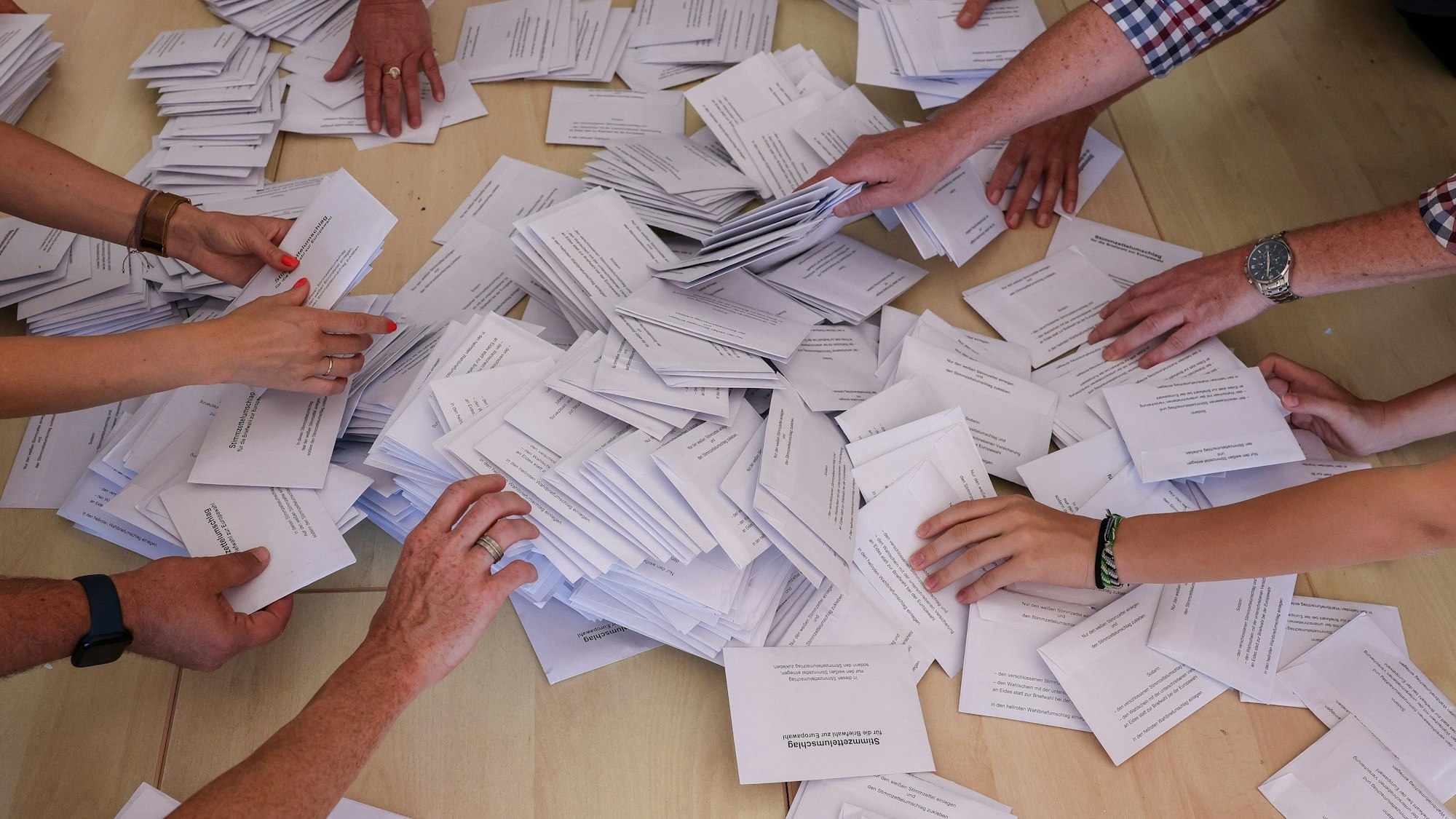 Sachsen-Anhalt, Halle: Zahlreiche Wahlhelfer nehmen sich bei der Stimmenauszählung die Umschläge mit den Briefwahlstimmen zur Europawahl.
