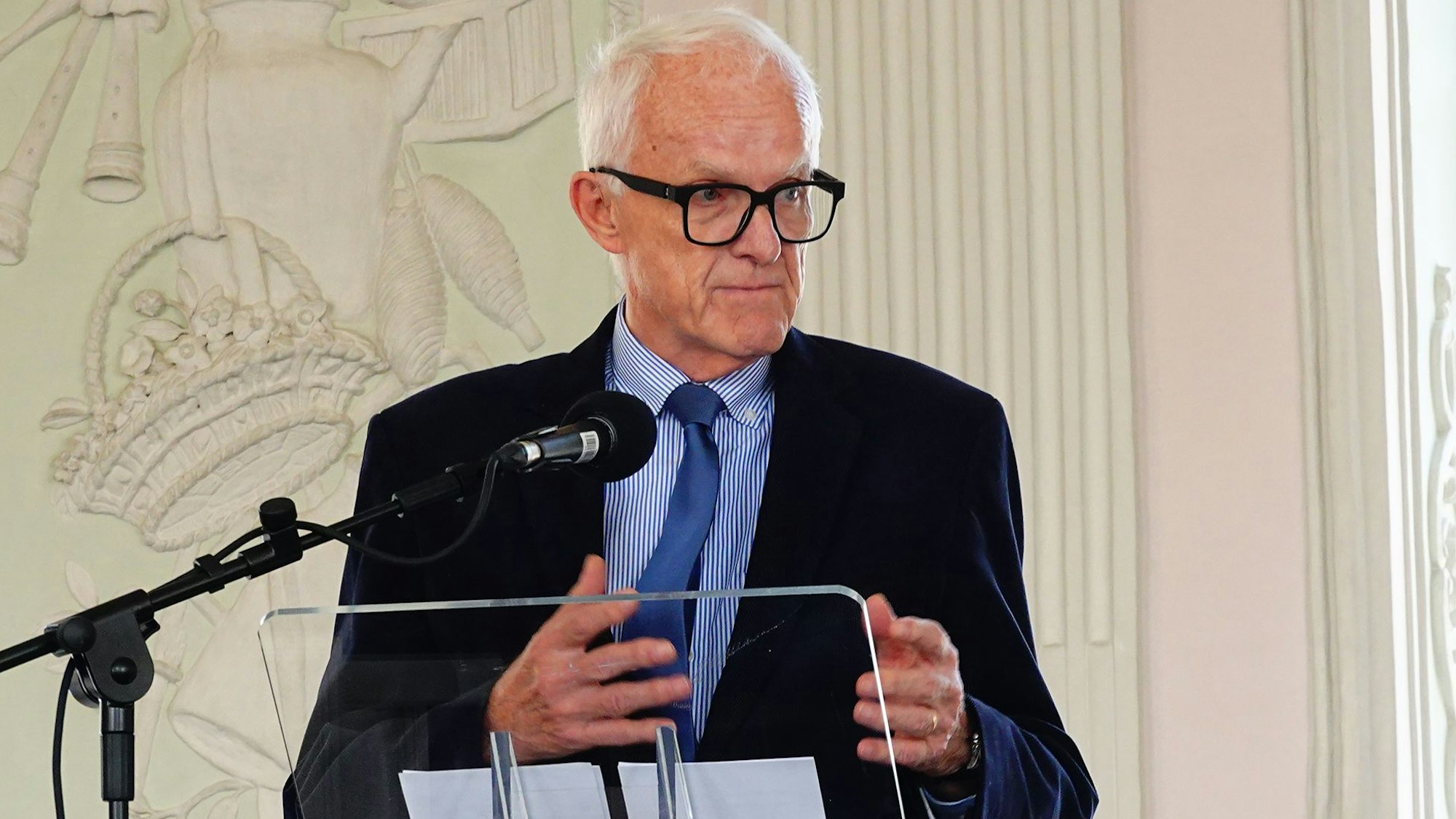 Auf dem Foto ist ein Mann an einem Rednerpult zu sehen.