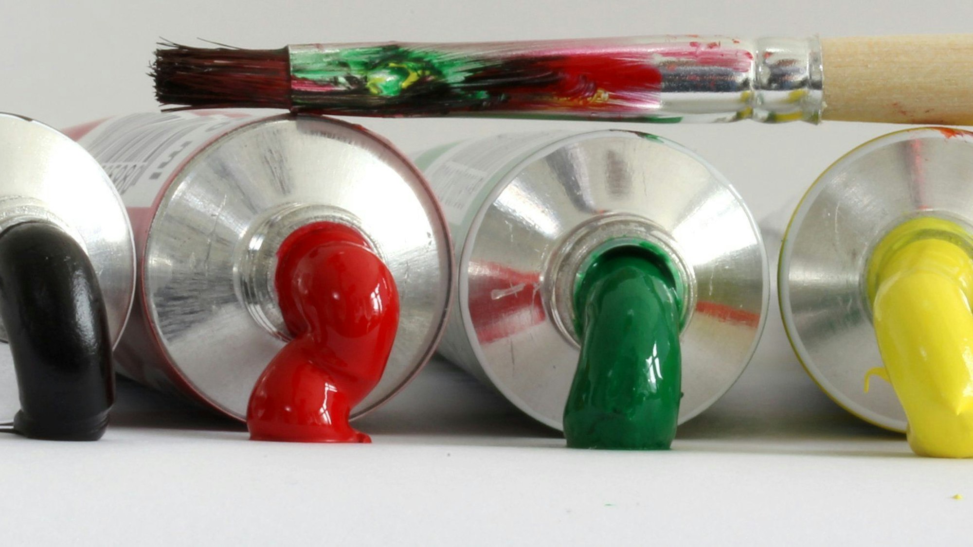 Farbtuben, aus denen Farbe läuft, liegen nebeneinander.