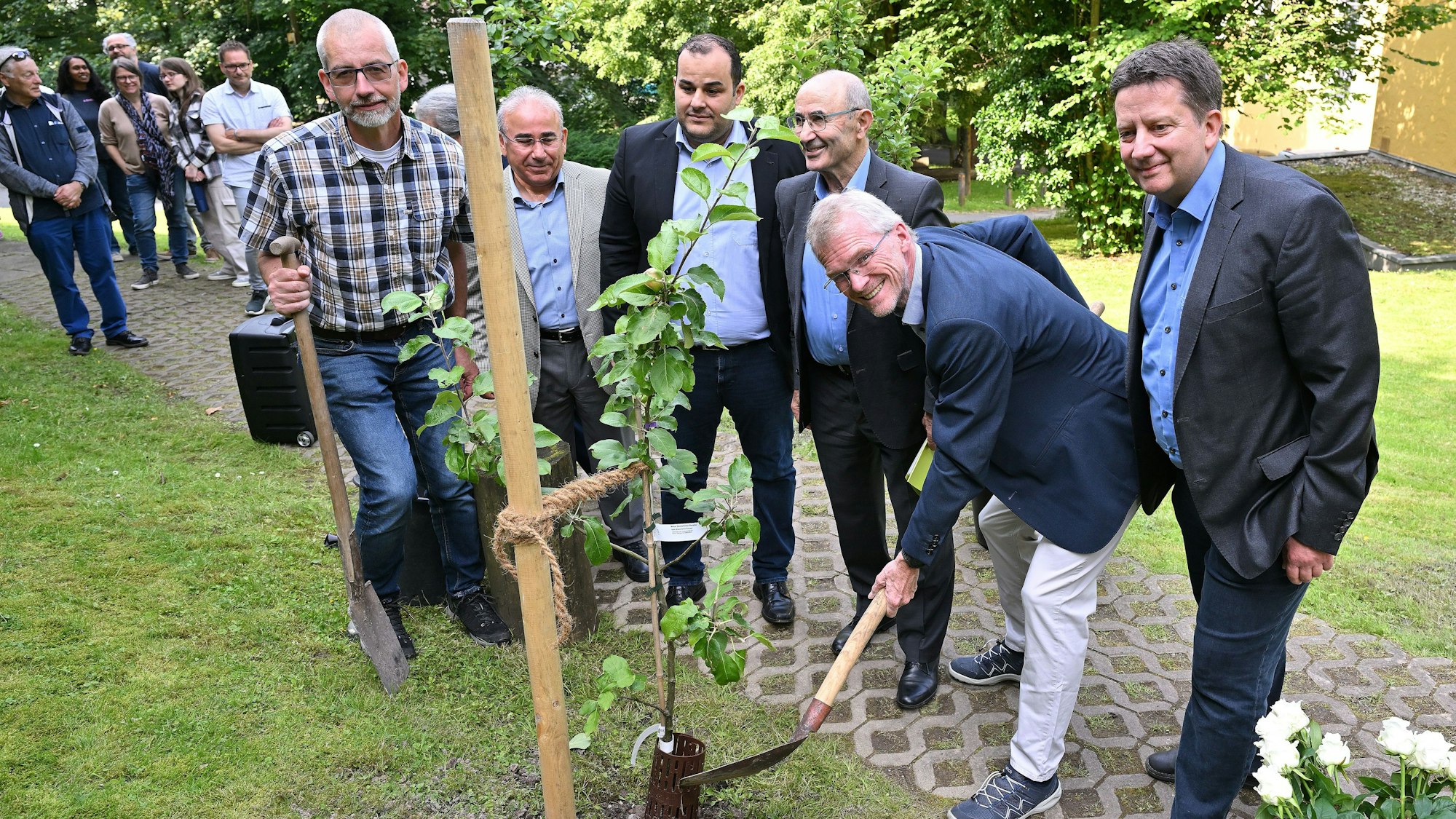 Gruppenbild mit Mahnmal: Bürgermeister Frank Stein (SPD) ist mit dem Spaten nahe am Baum.