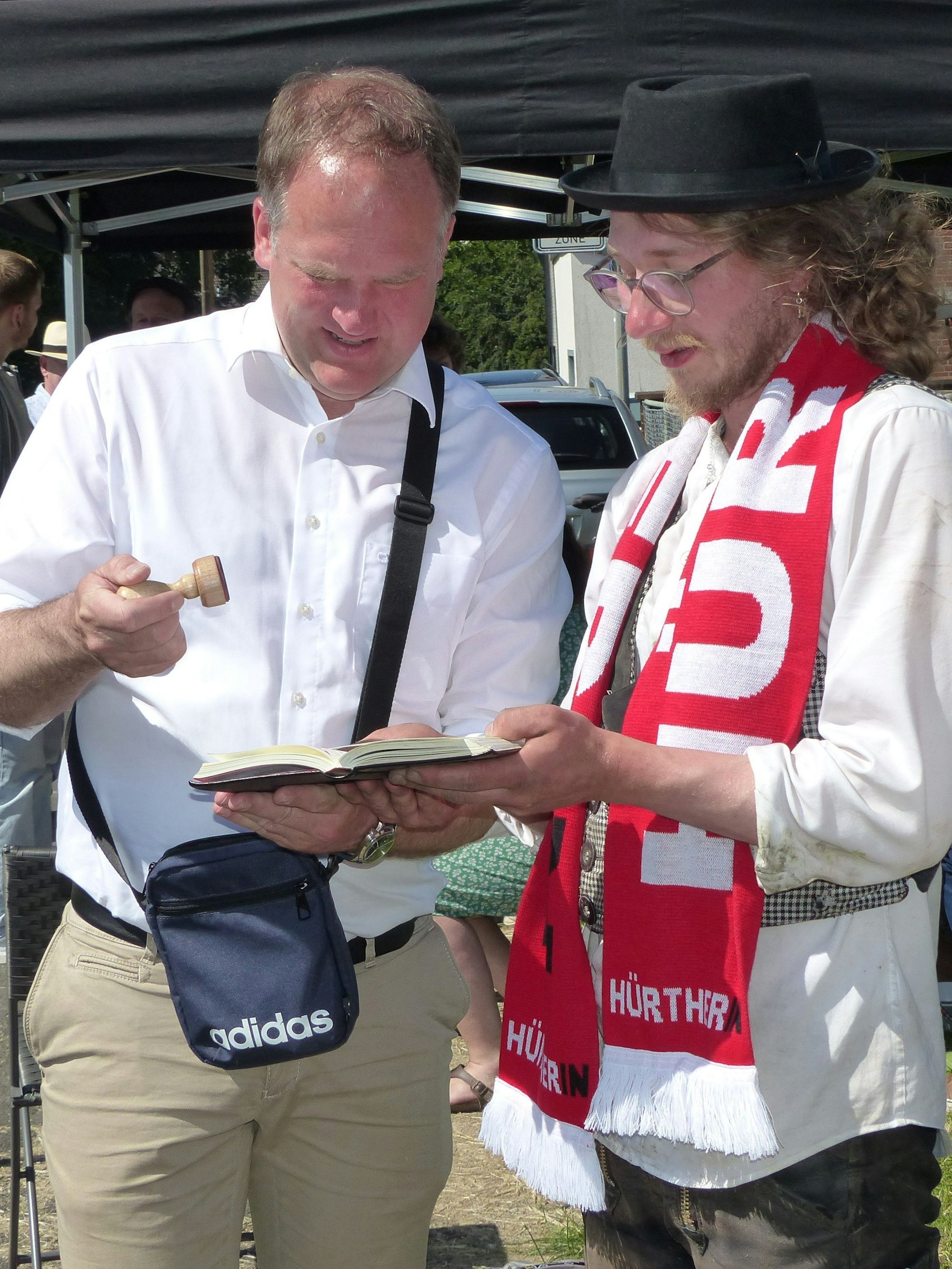 Bürgermeister Dirk Breuer drückt dem Walz-Heimkehrer Moritz David das Stadtsiegel ins Wanderbuch.
