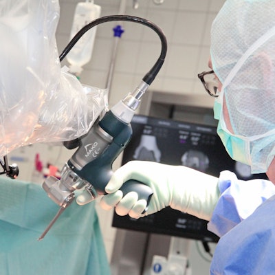 Ein Arzt führt den Arm des Roboters Richtung Operationstisch.