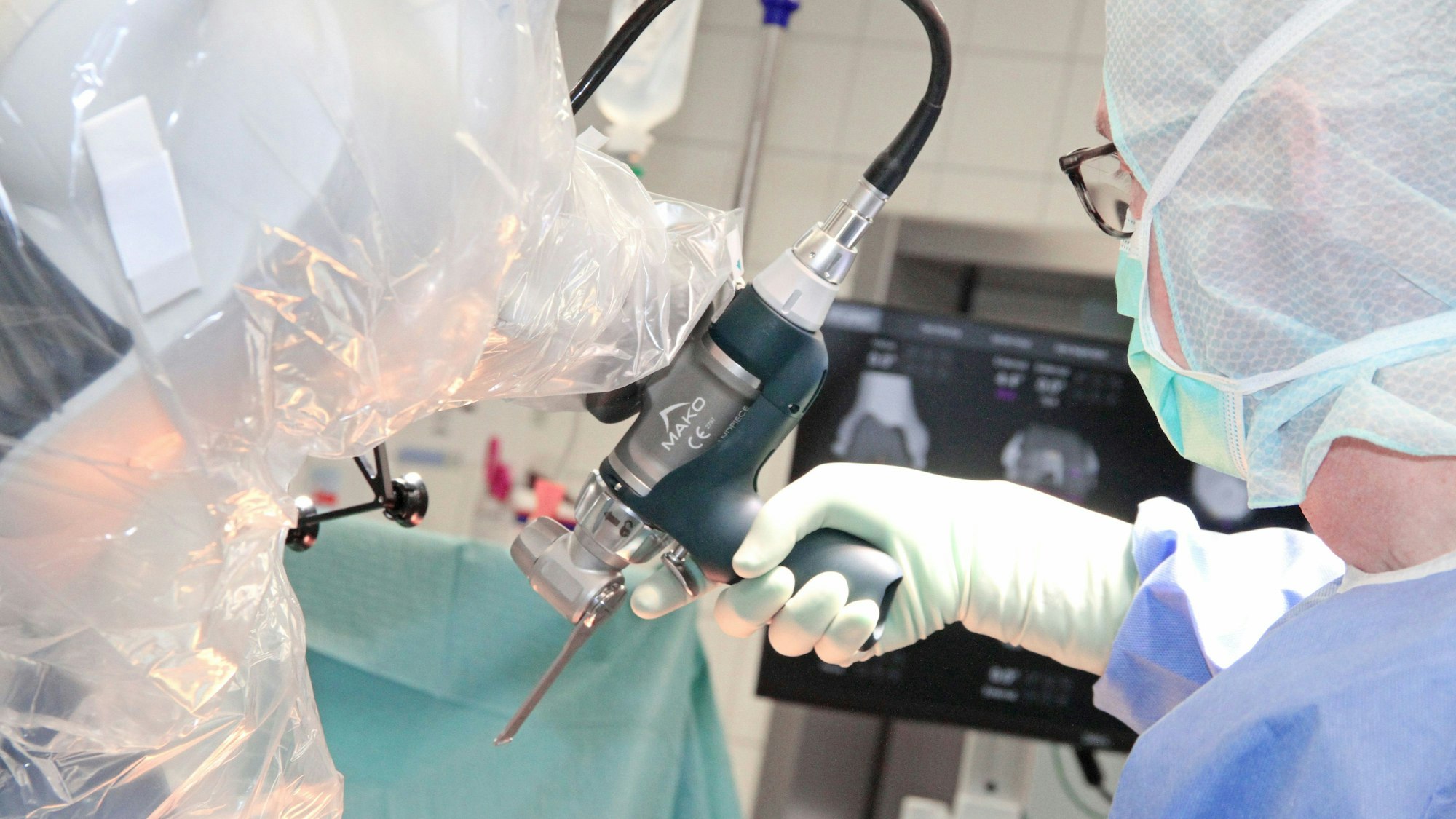 Ein Arzt führt den Arm des Roboters Richtung Operationstisch.