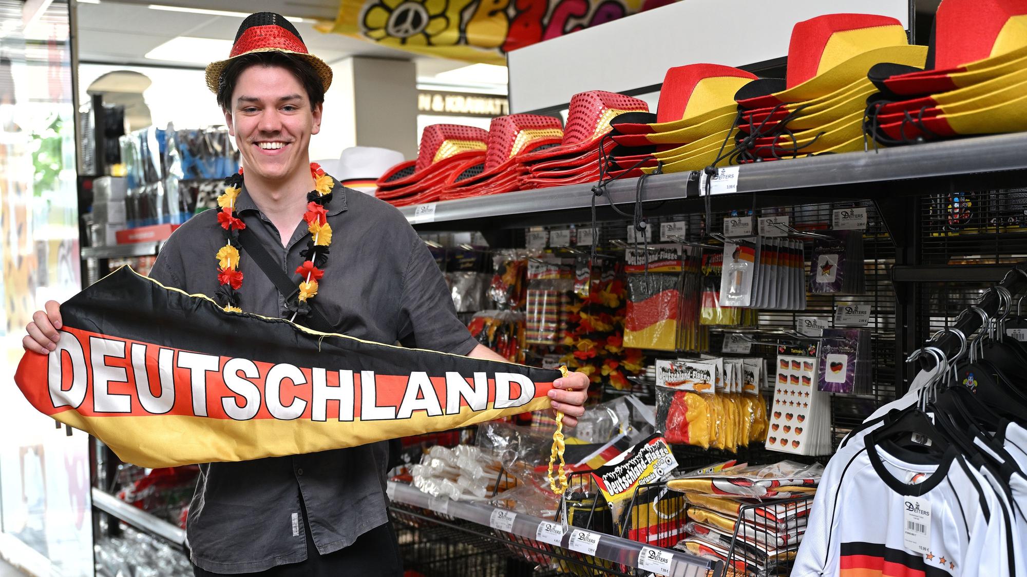Julius Neumann trägt Fanartikel und hält einen Deutschlandschal in den Händen.