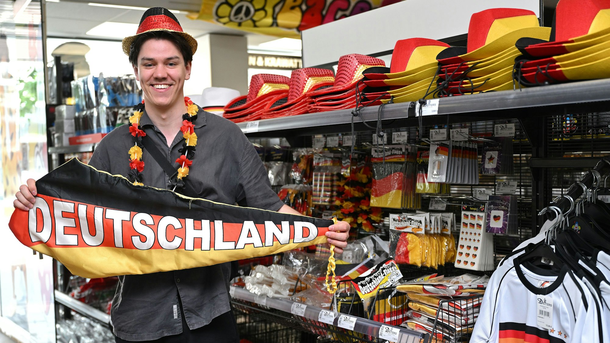 Julius Neumann trägt Fanartikel und hält einen Deutschlandschal in den Händen.