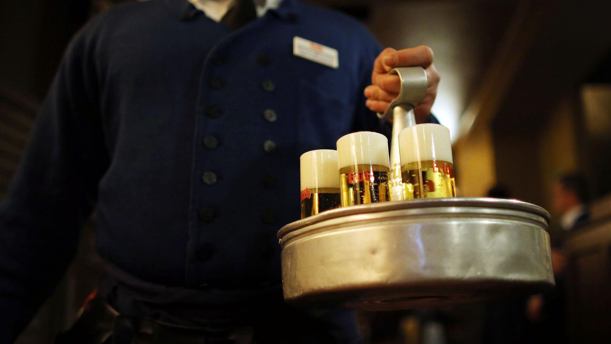 Ein Kellner bringt mehrere Gläser Kölsch.