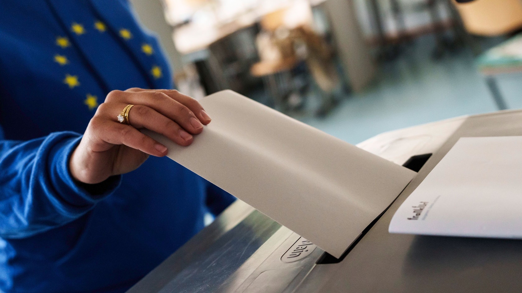 Eine Frau mit Europa-Hoodie wirft ihren Stimmzettel in die Urne.