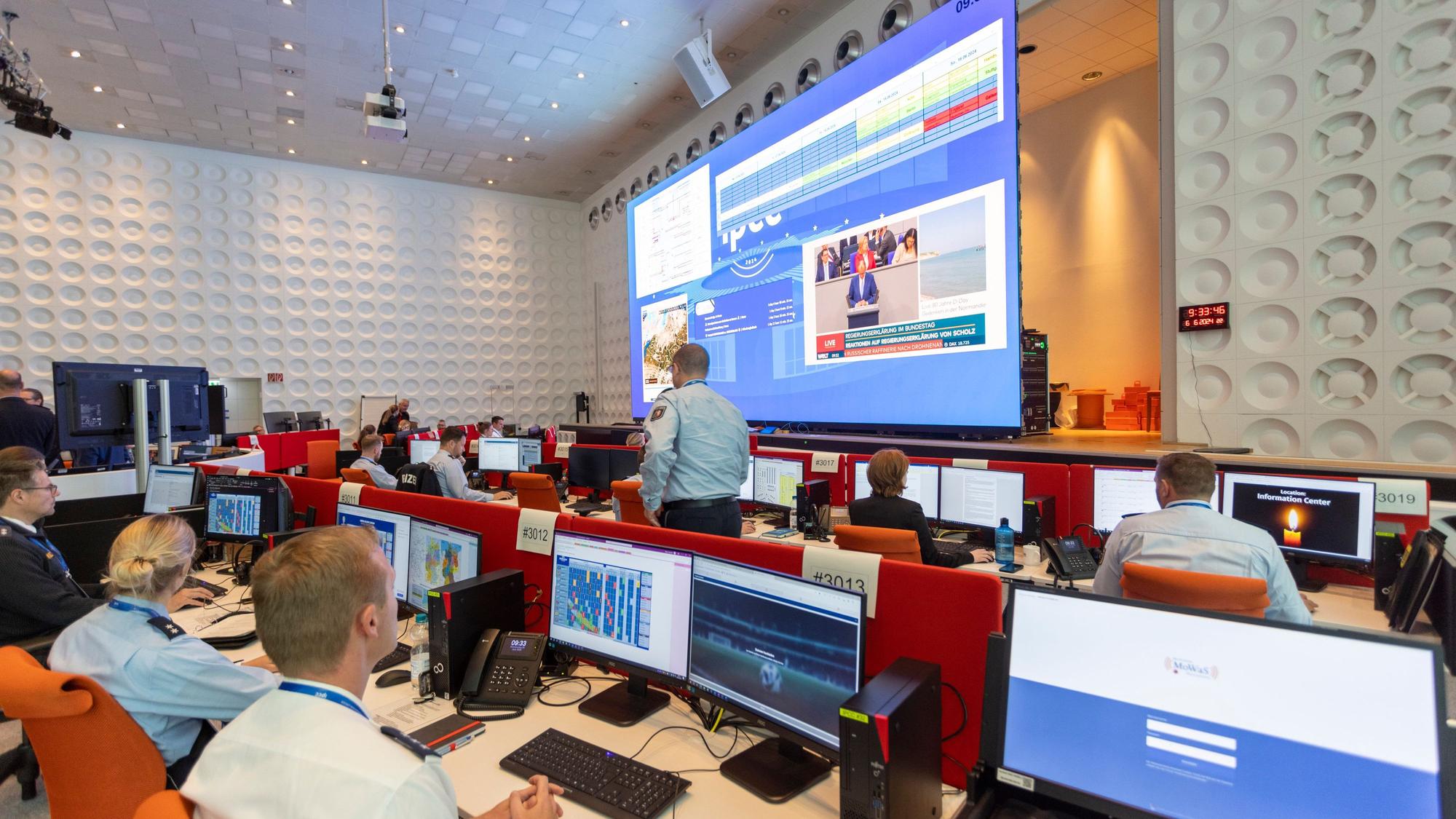 Polizeibeamte arbeiten gemeinsam an einem Arbeitsplatz im International Police Cooperation Center (IPCC) zur UEFA EURO 2024.