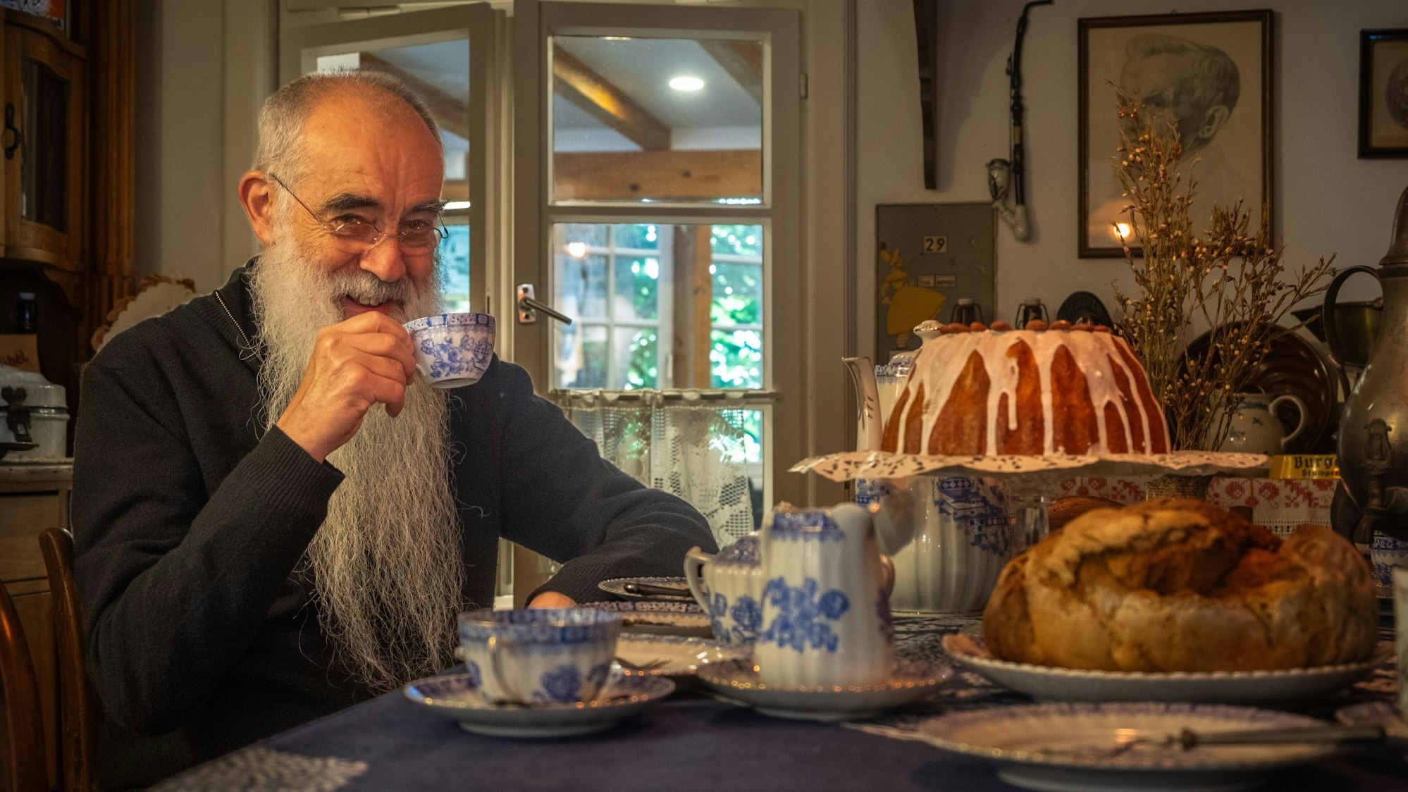 Foto eines Mannes, der bei Kaffee und Kuchen sitzt.