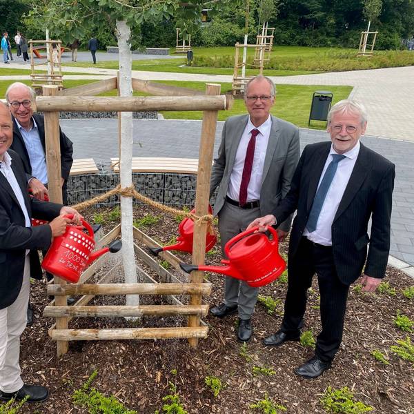 Zu sehen sind die für den Umbau Verantwortlichen beim Gießen eines der neu gepflanzten Bäume.
