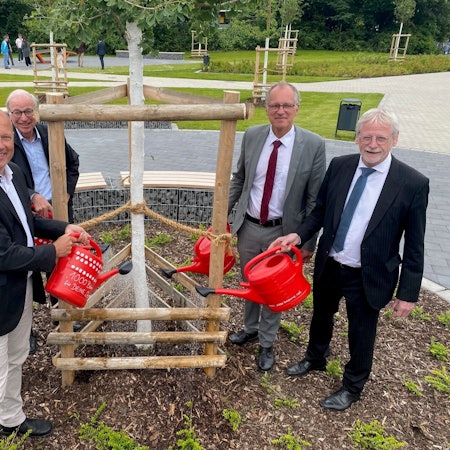 Zu sehen sind die für den Umbau Verantwortlichen beim Gießen eines der neu gepflanzten Bäume.