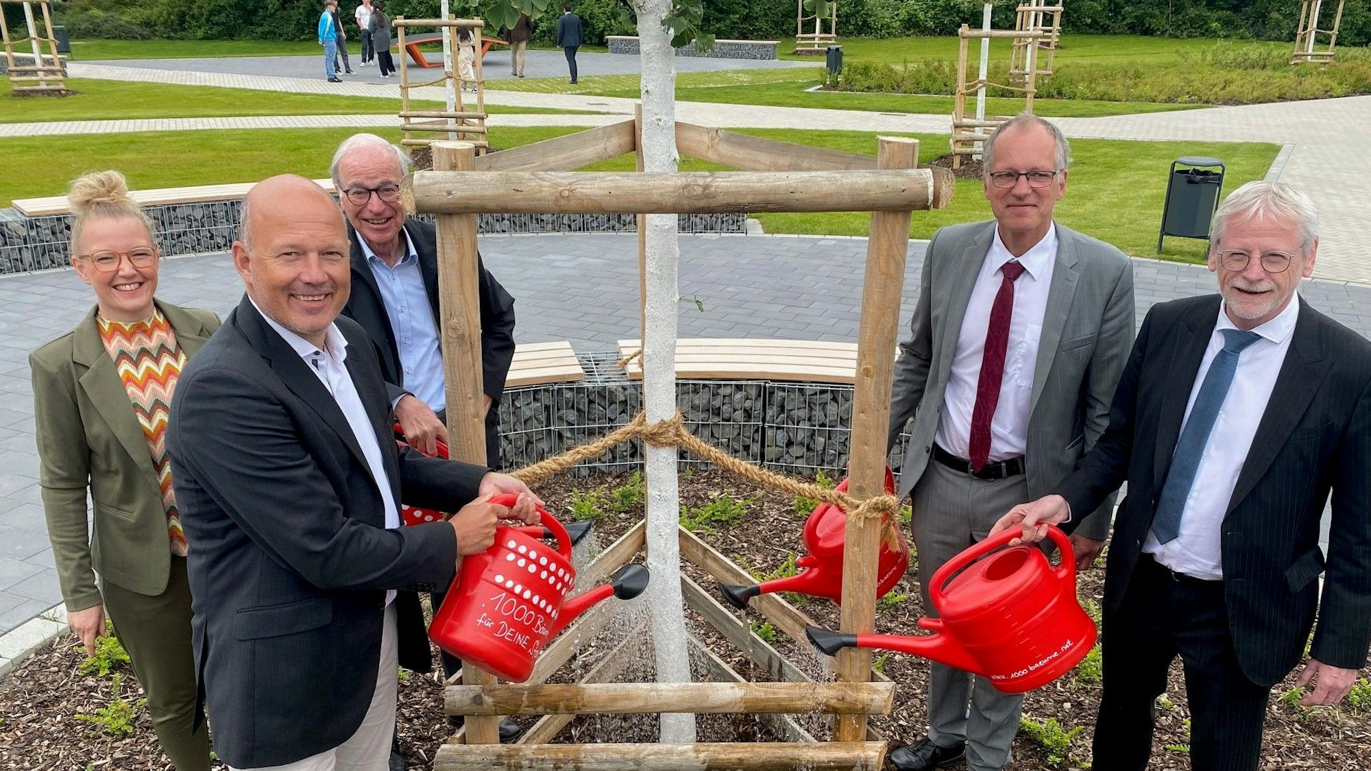 Zu sehen sind die für den Umbau Verantwortlichen beim Gießen eines der neu gepflanzten Bäume.