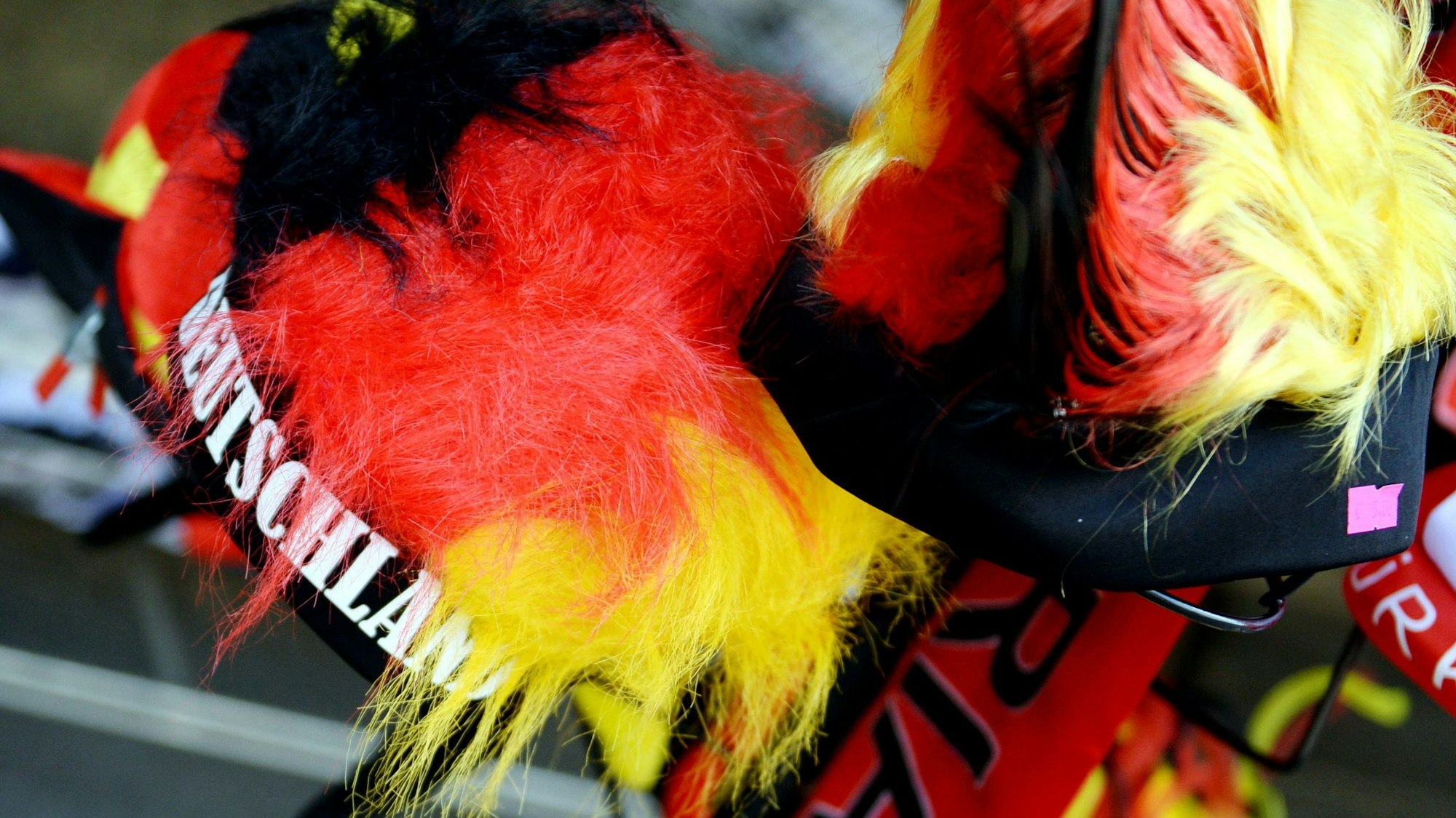 Verschiedene Kopfbedeckungen in den Farben der deutschen Flagge hängen in Berlin vor einem Laden.