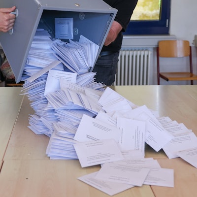 Zwei Wahlhelfer kippen eine Wahlurne mit den Briefwahlstimmen nach der Europawahl in einem Briefwahllokal zur Stimmenauszählung auf einen Tisch.