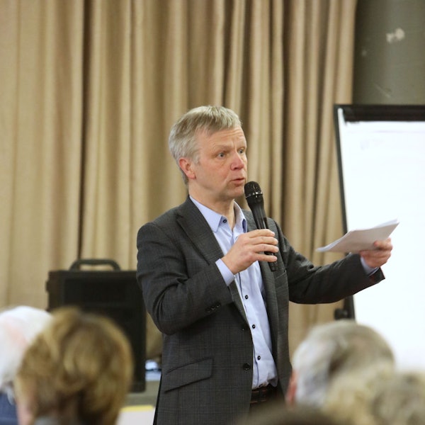 Ein Mann mit einem Mikrofon und einem Zettel in den Händen.