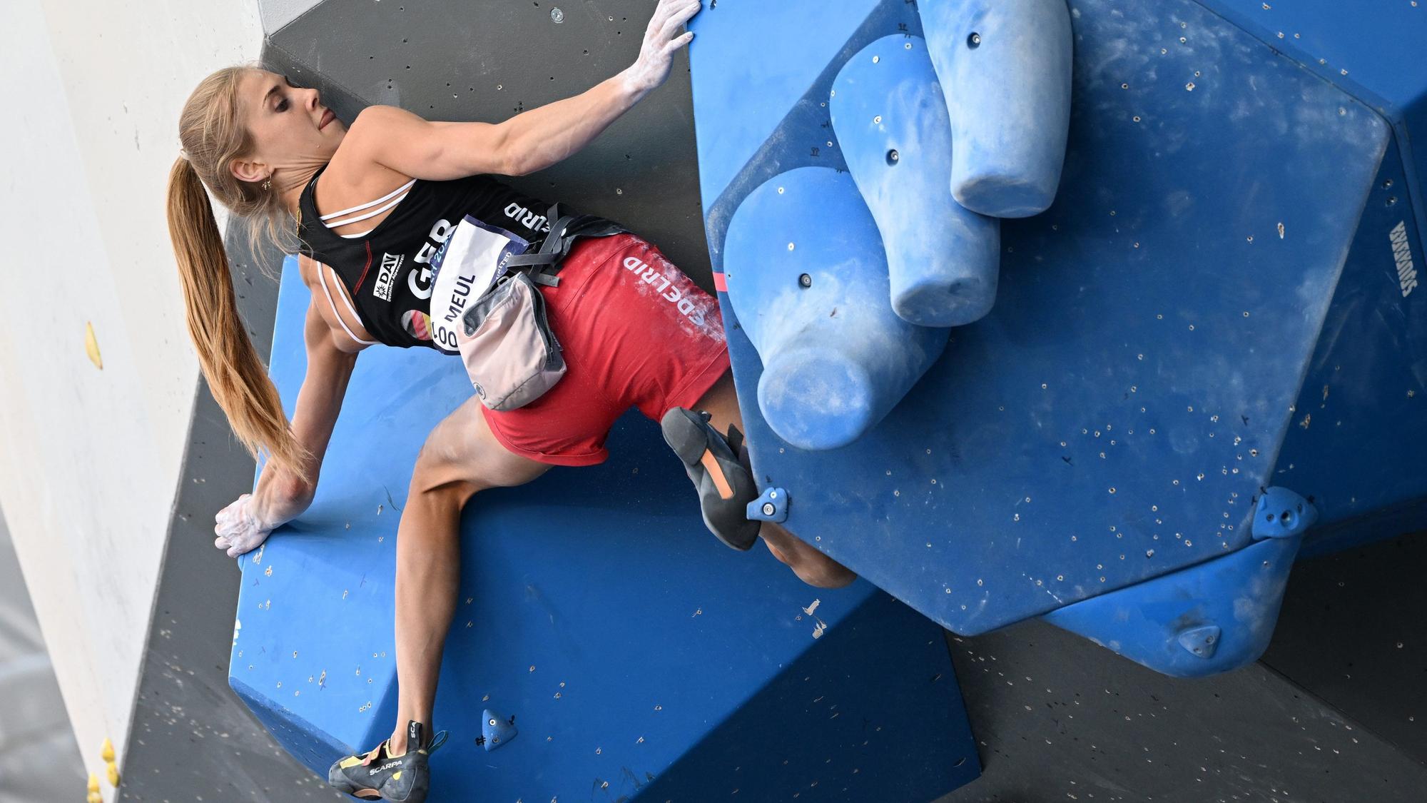 Eine Frau bouldert an einer Wand einer Kletterhalle.