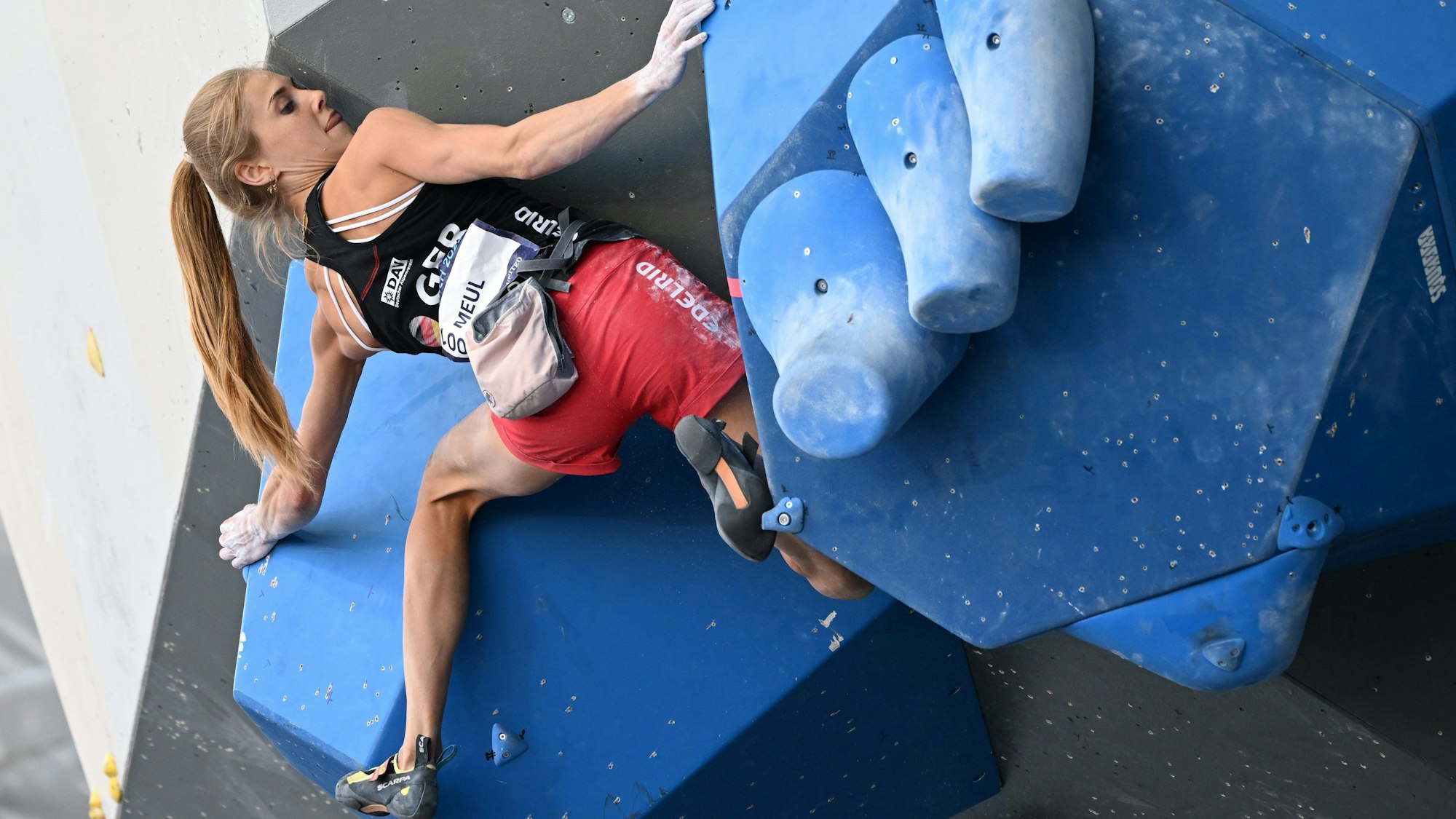 Eine Frau bouldert an einer Wand einer Kletterhalle.