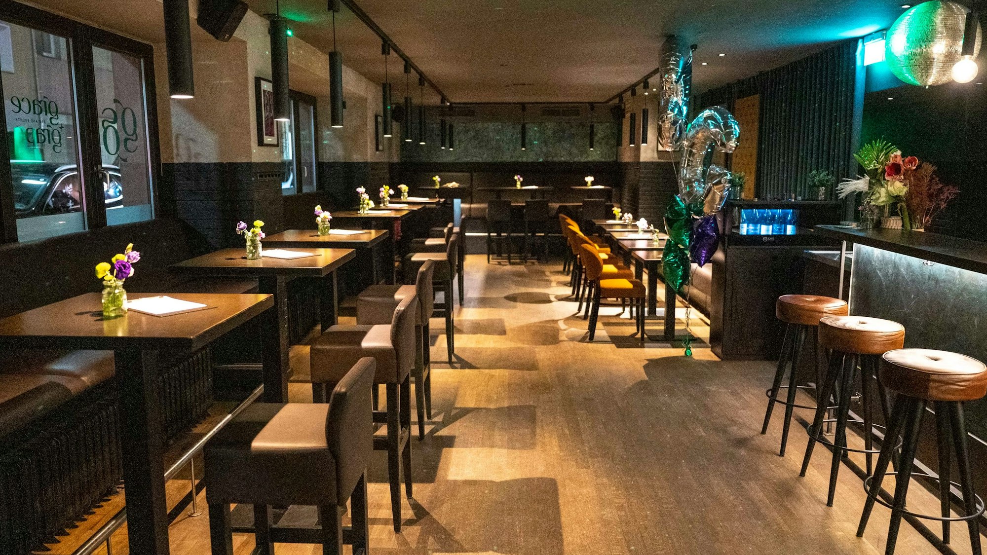Zu sehen ist eine Bar von innen, mit Tischen und Stühlen.