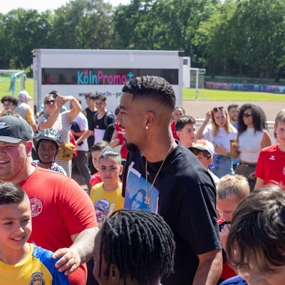 Fußball-Nationalspieler Benjamin Henrichs wird bei seiner Ankunft auf dem Sommerfest der Sportvereinigung Porz von jungen Kickern umringt.