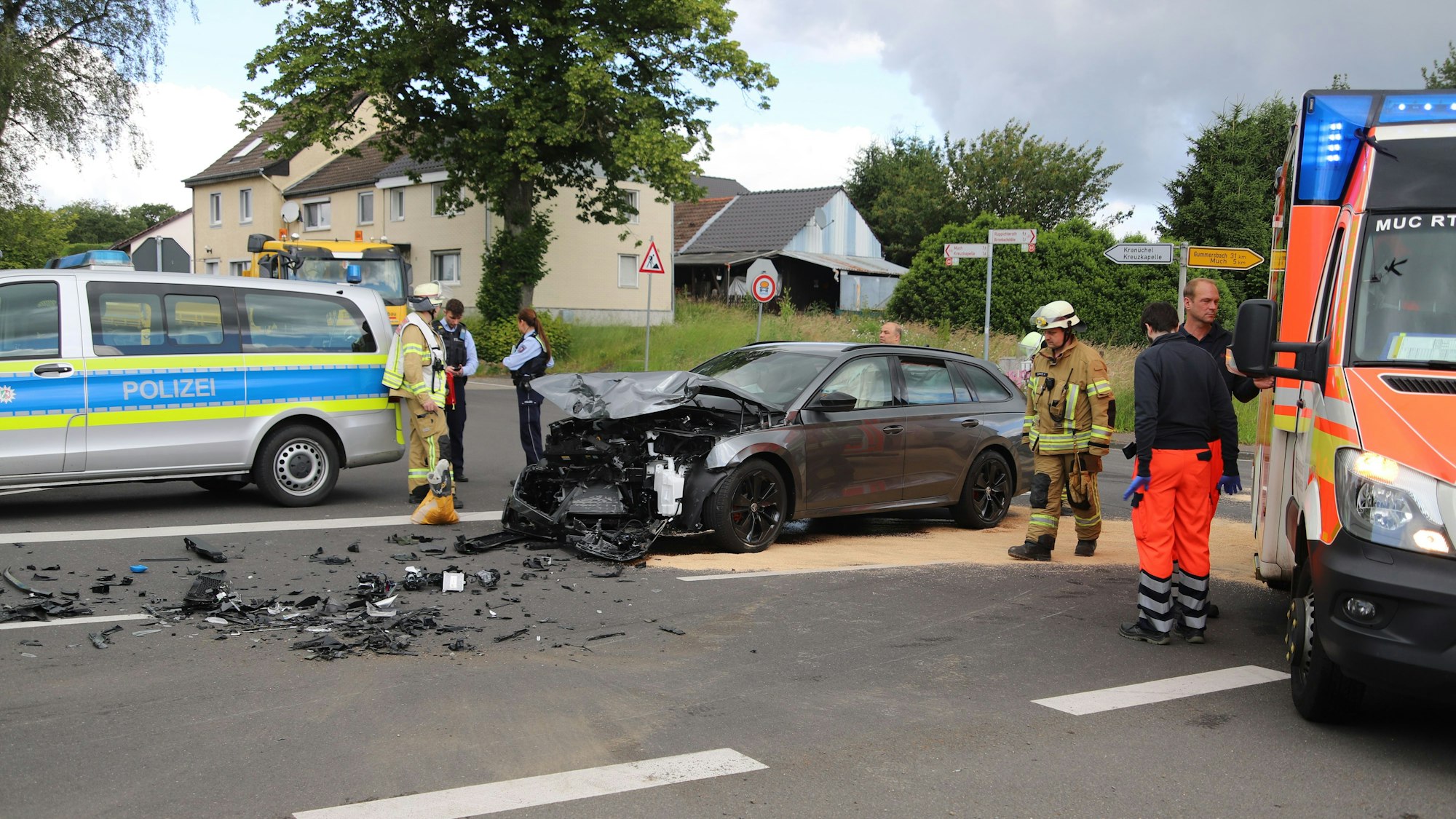 Ein demoliertes Auto steht zwischen einem Polizeiwagen und einem Rettungswagen.
