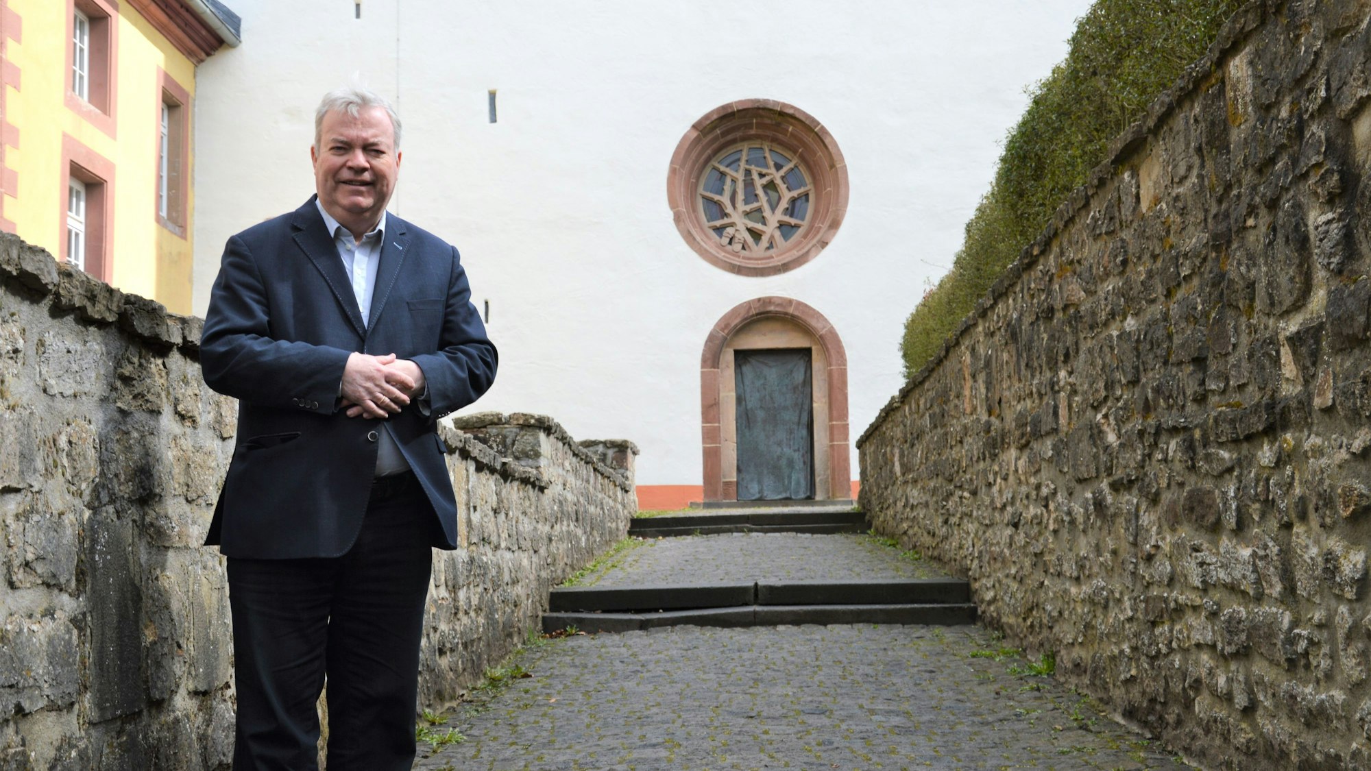 Helmut J. Kirfel steht vor der Steinfelder Basilika.