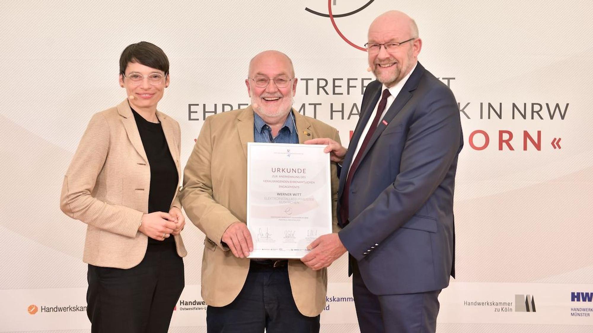 Josefine Paul und Berthold Schröder stehen links und rechts von Werner Witt, der seine Urkunde zeigt.