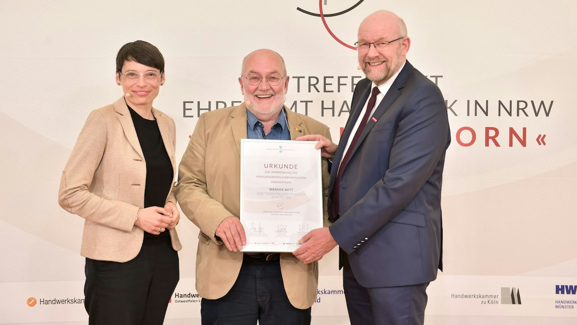 Josefine Paul und Berthold Schröder stehen links und rechts von Werner Witt, der seine Urkunde zeigt.