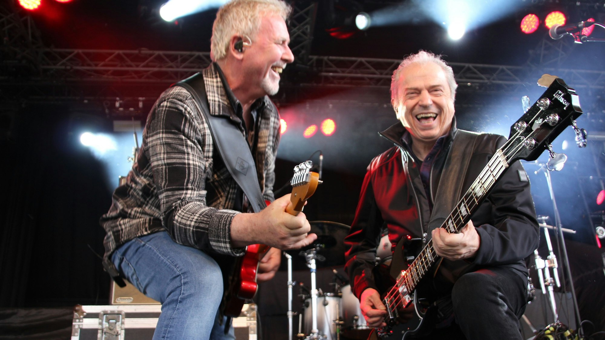 Zwei Gitarristen knien nebeneinander am Bühnenrand. Beide haben sichtlich Spaß an dem, was sie tun.