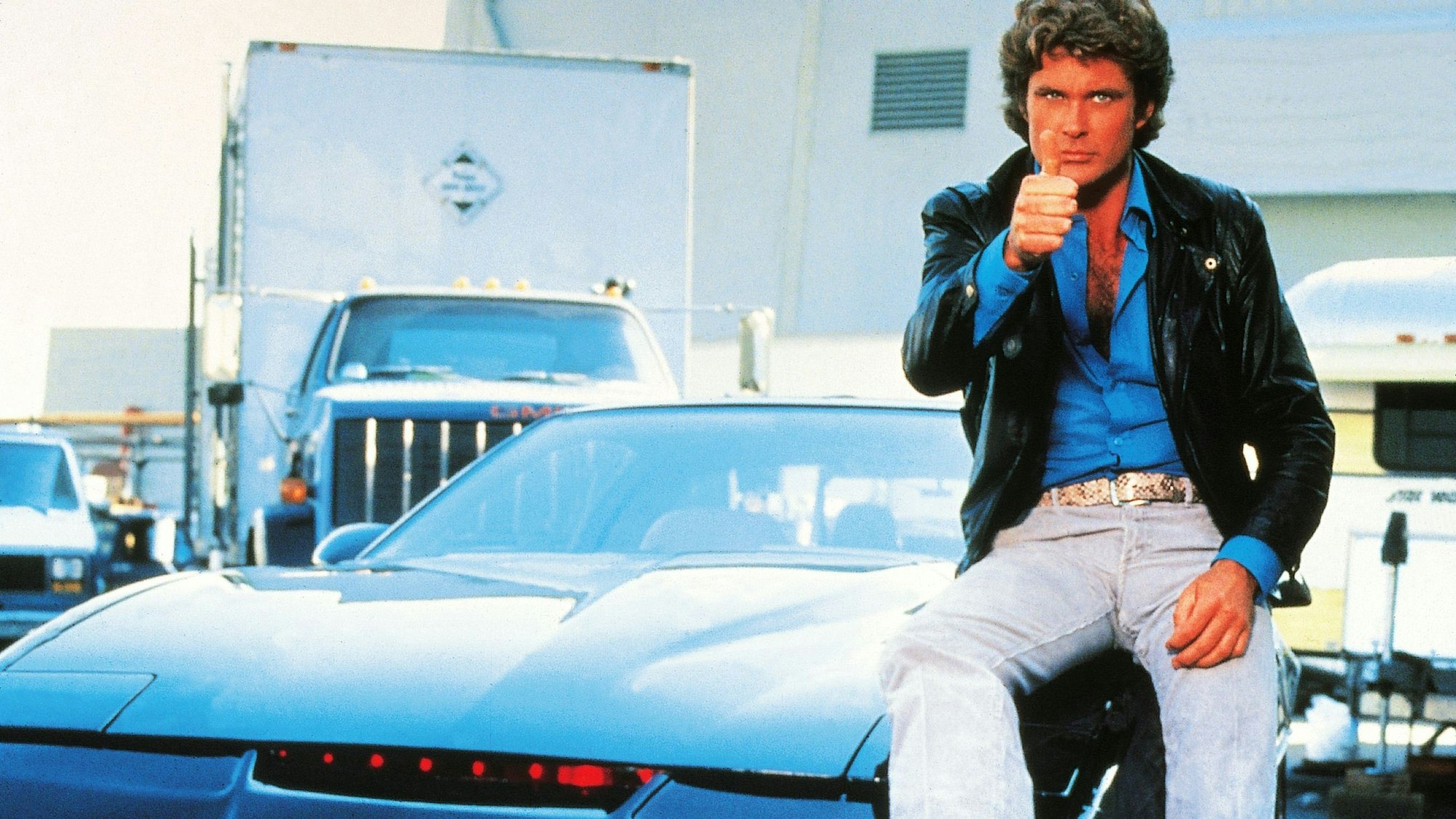 David Hasselhoff sitzt auf K.I.T.T. und zeigt den Daumen hoch.