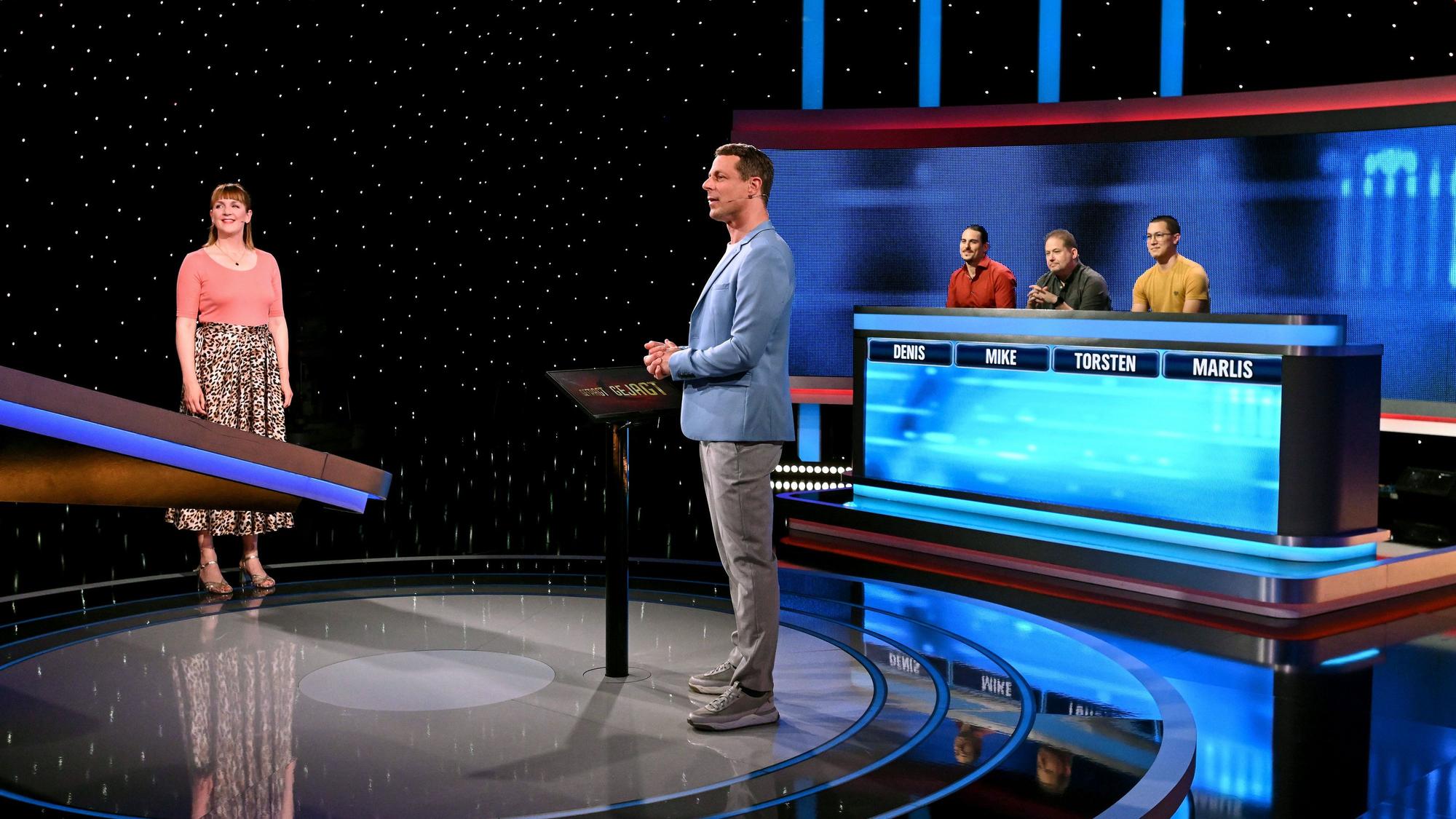WDR-2-Moderatorin Marlis Schaum steht gemeinsam mit Moderator Alexander Bommes vor dem Jäger-Stuhl in der Quizshow „Gefragt – Gejagt“.