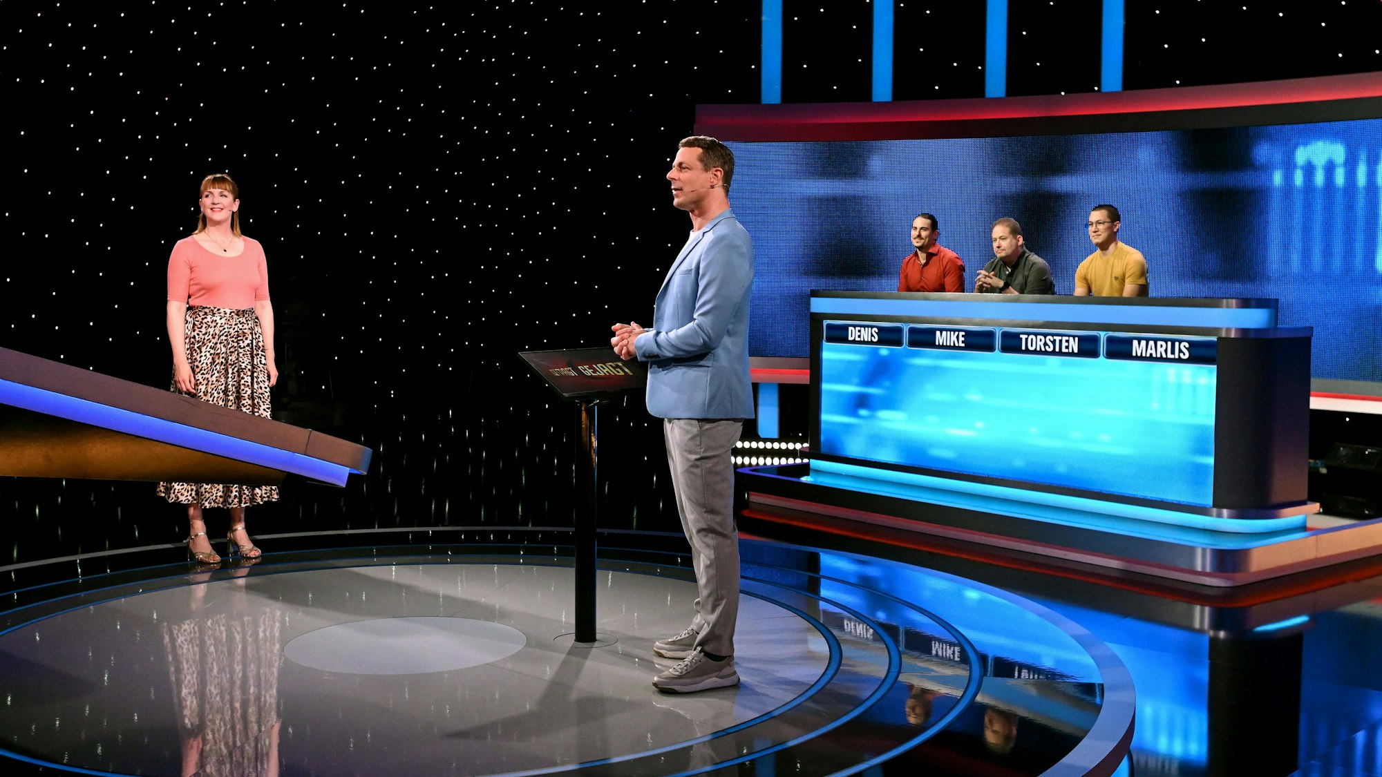 WDR-2-Moderatorin Marlis Schaum steht gemeinsam mit Moderator Alexander Bommes vor dem Jäger-Stuhl in der Quizshow „Gefragt – Gejagt“.