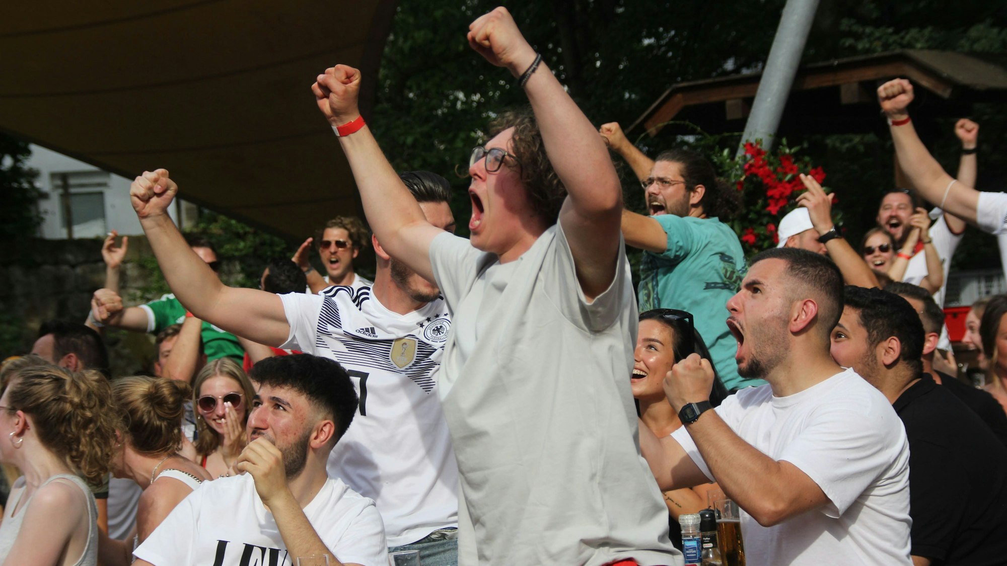 Menschen, zum Teil in Trikots, springen in die Höhe und jubeln.