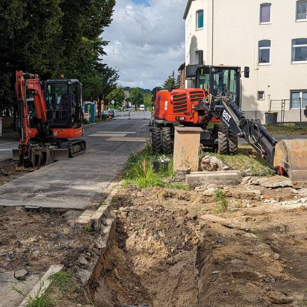 Das Foto zeigt zwei Bagger vor Baugruben an einer abgesperrten Straße.