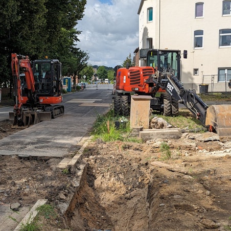 Das Foto zeigt zwei Bagger vor Baugruben an einer abgesperrten Straße.