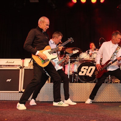 Sämtliche Musiker der britischen Rockband Status Quo posen vor dem Schlagzeug.