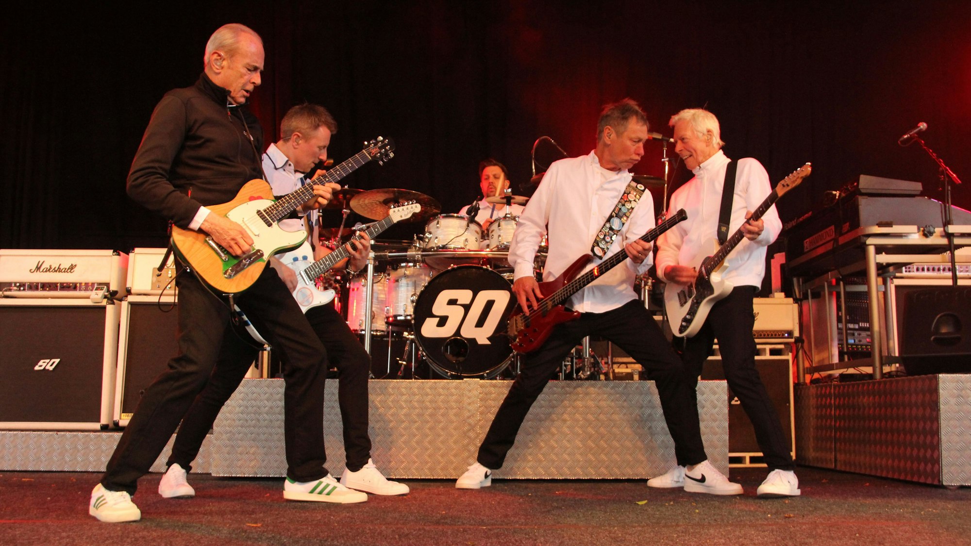 Sämtliche Musiker der britischen Rockband Status Quo posen vor dem Schlagzeug.