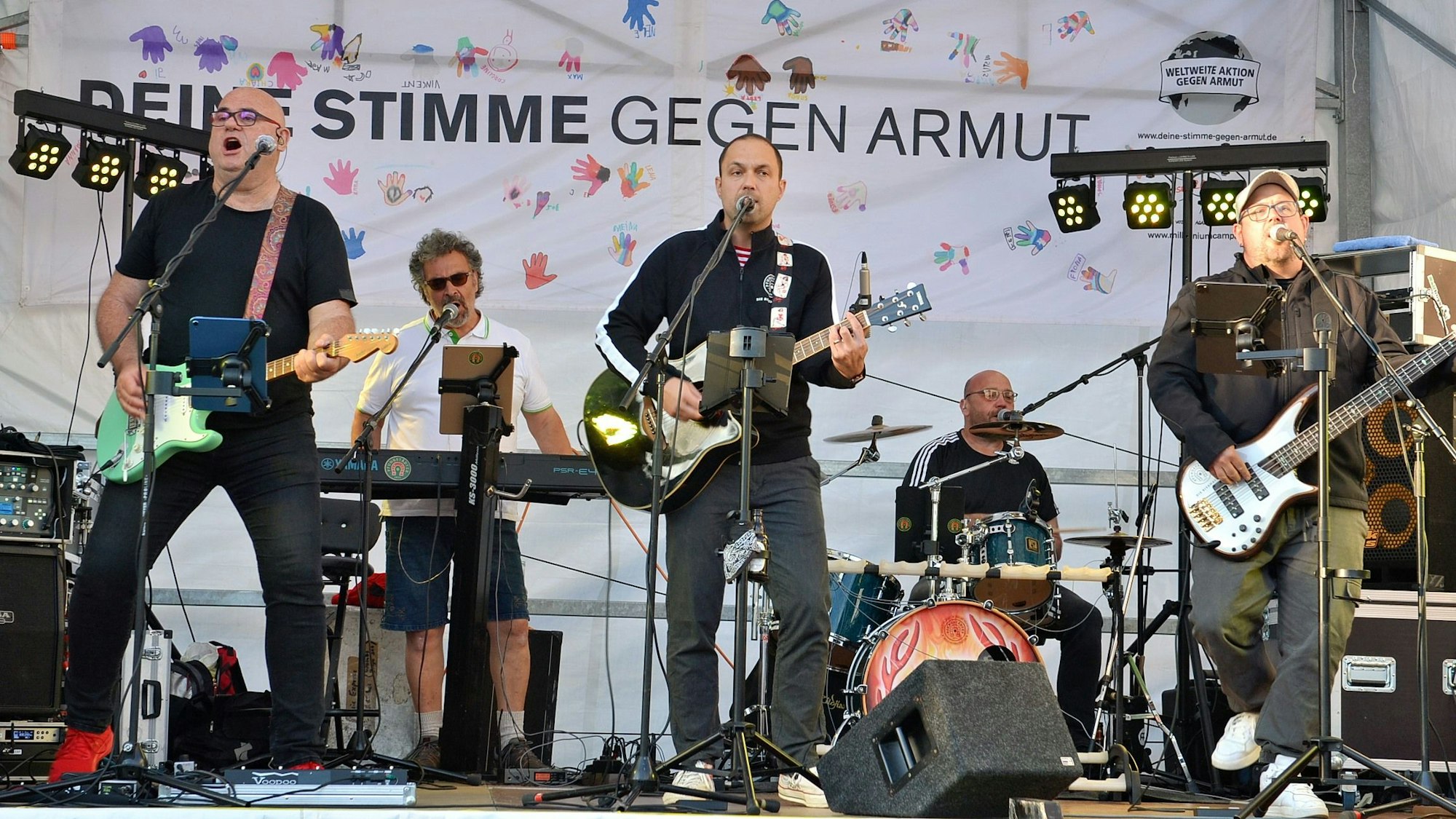 Die Musiker der Band „Wömbe Jonge“ stehen auf der Bühne und spielen ihre Instrumente.