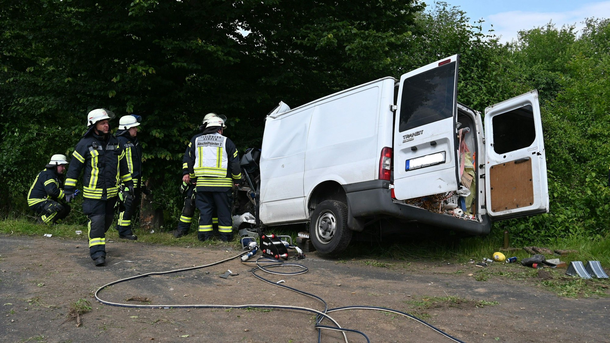 Auf dem Bild ist der Unfallwagen zu sehen, Feuerwehrleute arbeiten an der Unfallstelle.