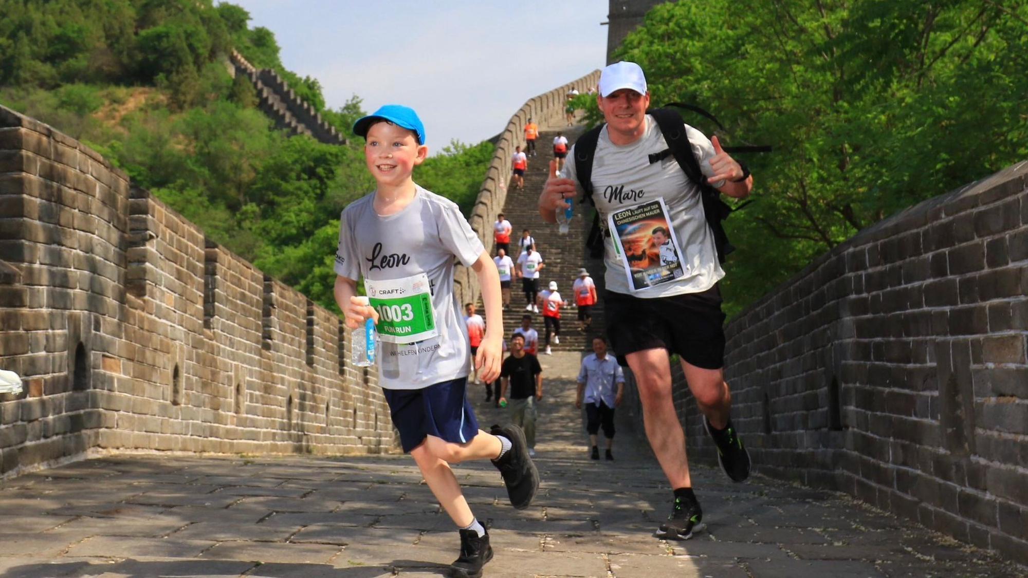 Leon und Vater Marc Marth tragen Kappen und laufen die Stufen der Chinesischen Mauer herunter.