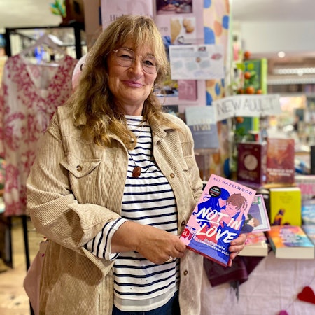 Renate Elsen steht in der Bücherecke in Blankenheim und präsentiert das Buch „Not in Love“ von Ali Hazelwood.