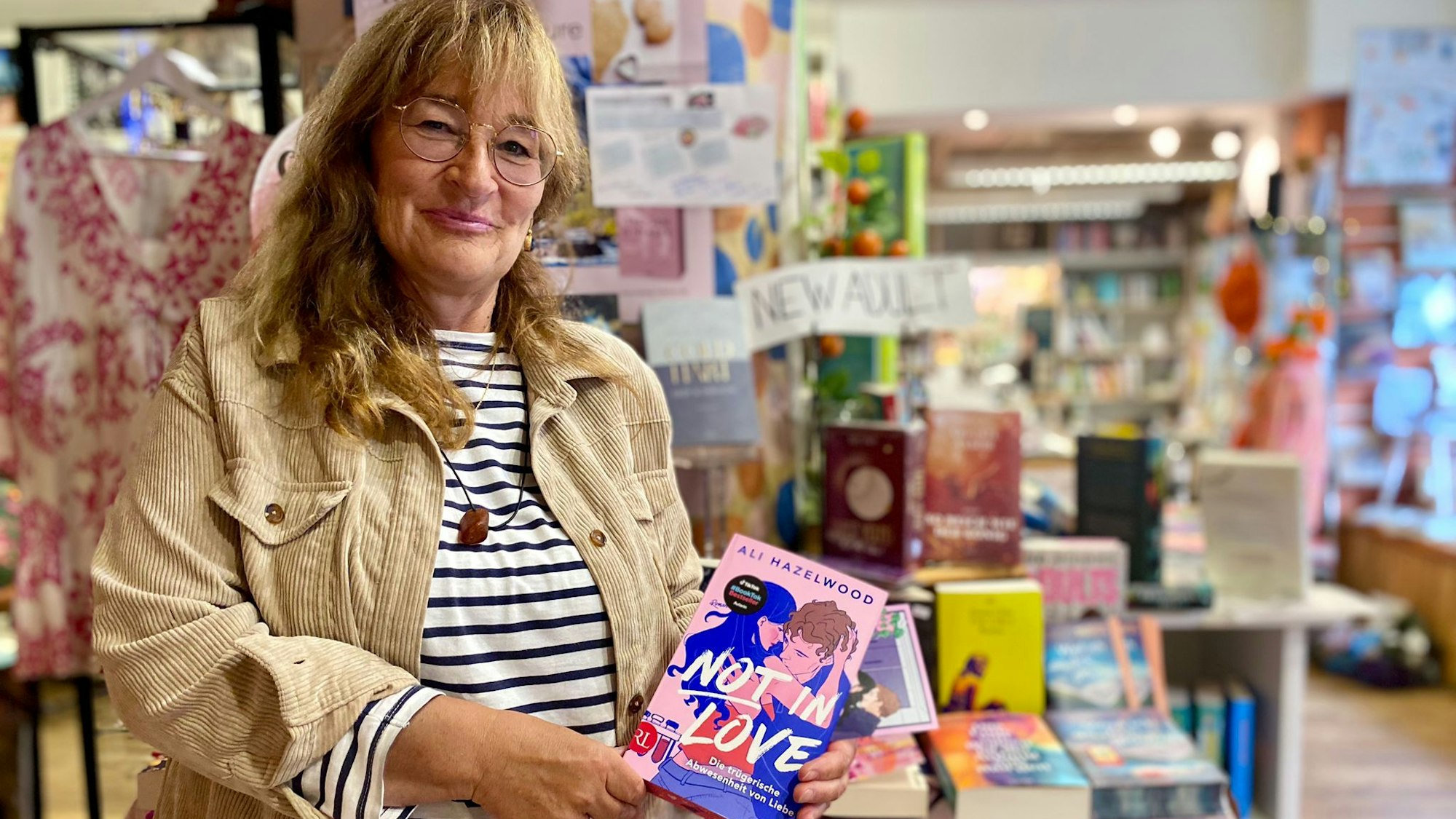 Renate Elsen steht in der Bücherecke in Blankenheim und präsentiert das Buch „Not in Love“ von Ali Hazelwood.