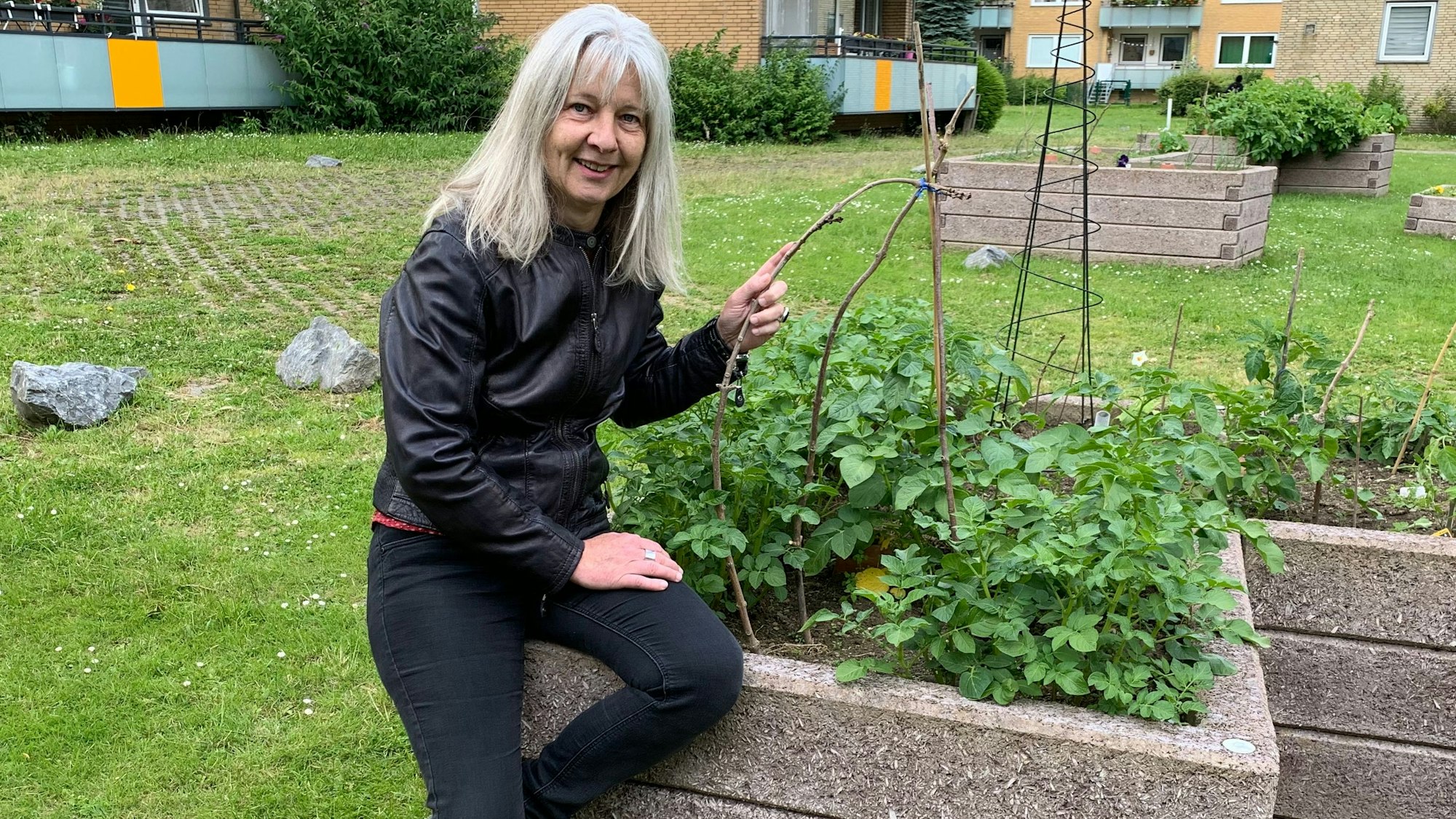 Eine Frau sitzt auf dem Rand eines Pflanzenbeetes.