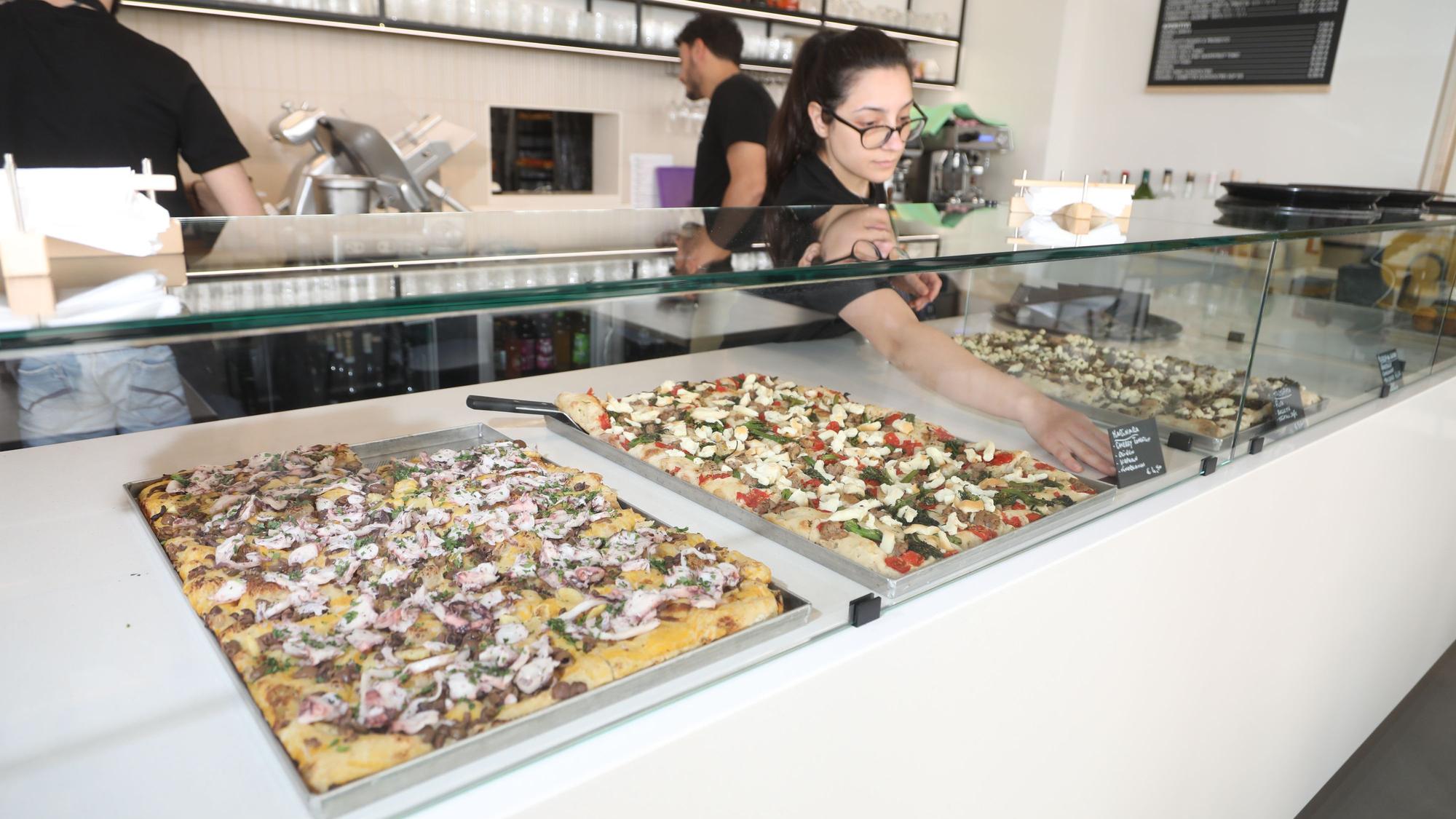 verschiedene Sorten Focaccia werden von einer Mitarbeiterin in eine Theke einsortiert