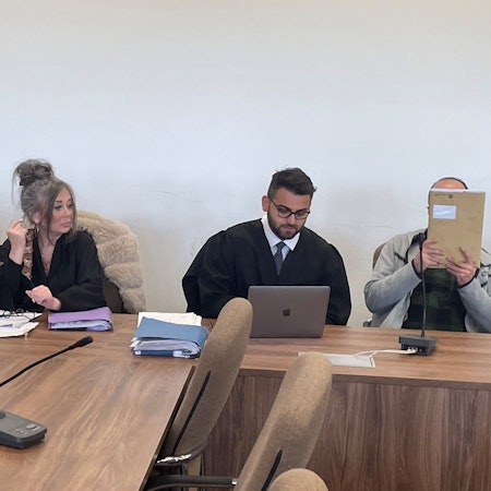 Die Angeklagten, dazwischen ihre Verteidiger, versteckten sich beim Prozessauftakt hinter einer Jacke und einer Mappe vor den Pressefotografen.