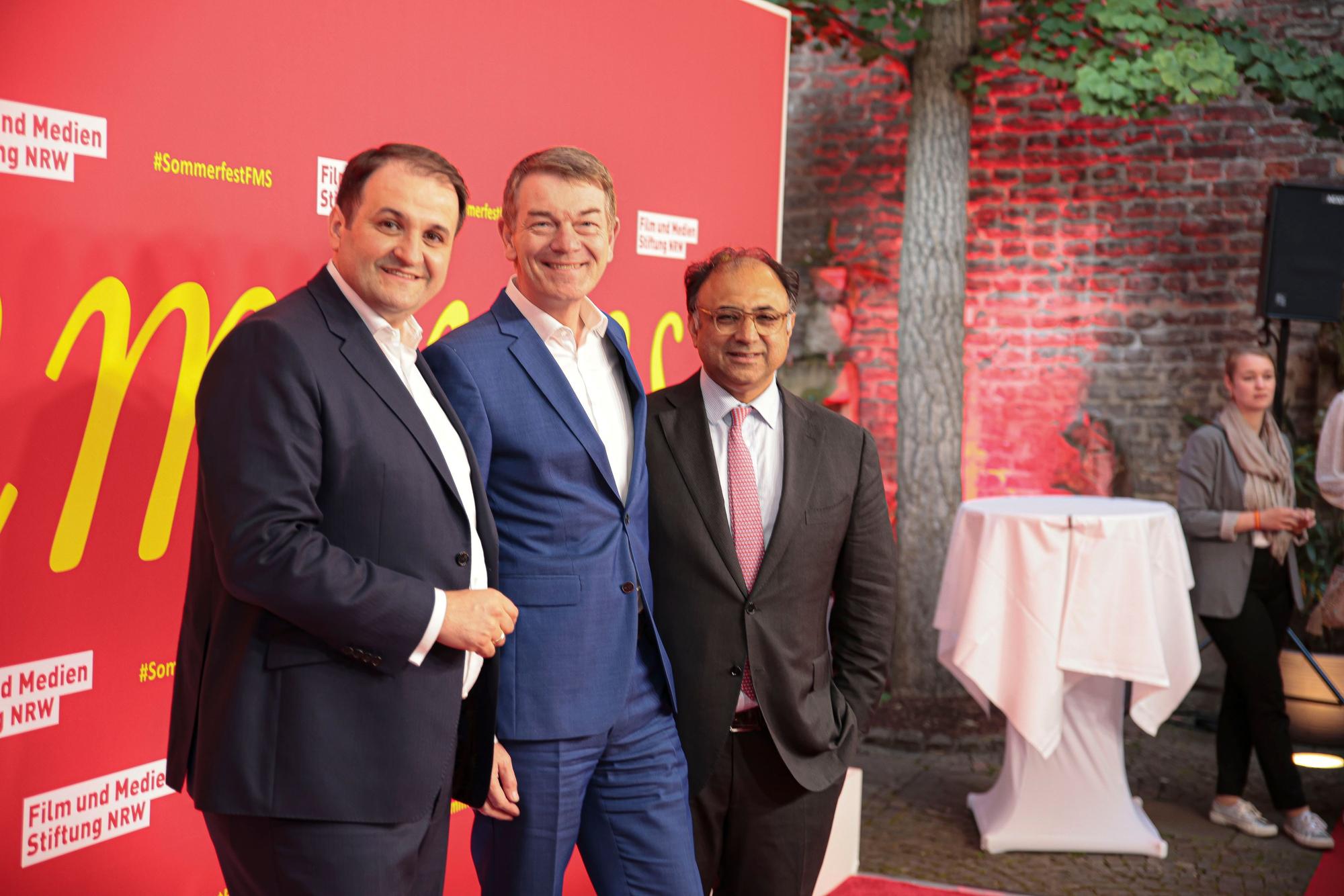 Nathanael Liminski (NRW Minister Medien), Jörg Schönenborn (Programmdirektor WDR) und Walid Nakschbandi (Leiter Filmstiftung NRW) stehen zusammen auf einem Roten Teppich.