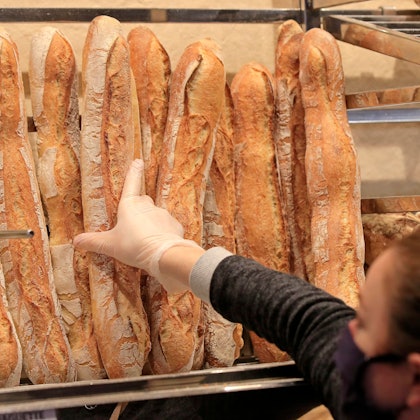 Eine Verkäuferin nimmt ein Baguette in einer Bäckerei.